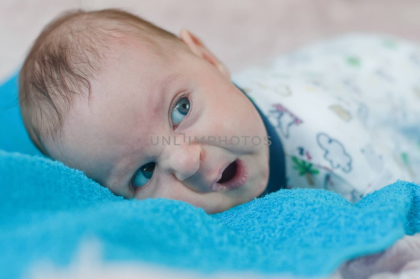 Discontented baby on the blue towel by Linaga