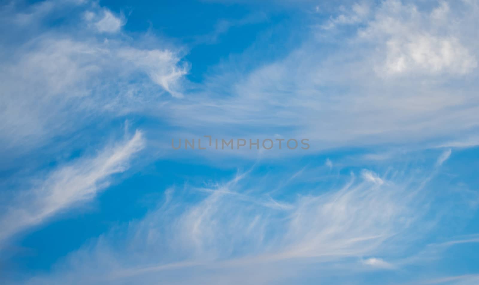 Blue boundless sky with the fluffy white clouds