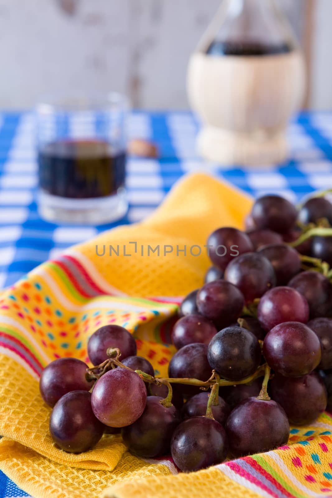 Closeup of a bunch of red grapes and a glass of red wine with a  by LuigiMorbidelli
