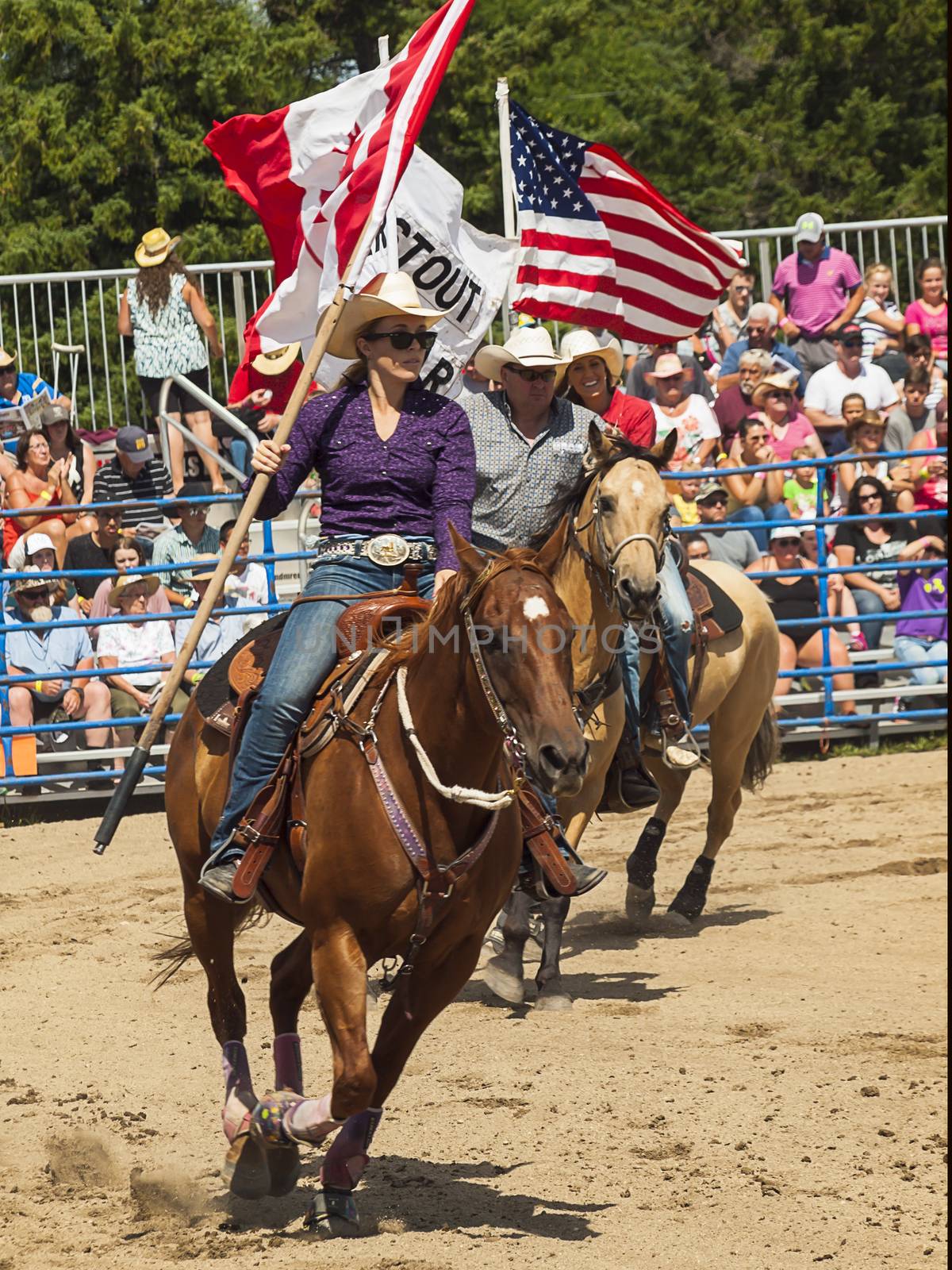 Rodeo.  A man and a woman with the flags of Canada and America on horseback.  Winnipeg.  Canada.