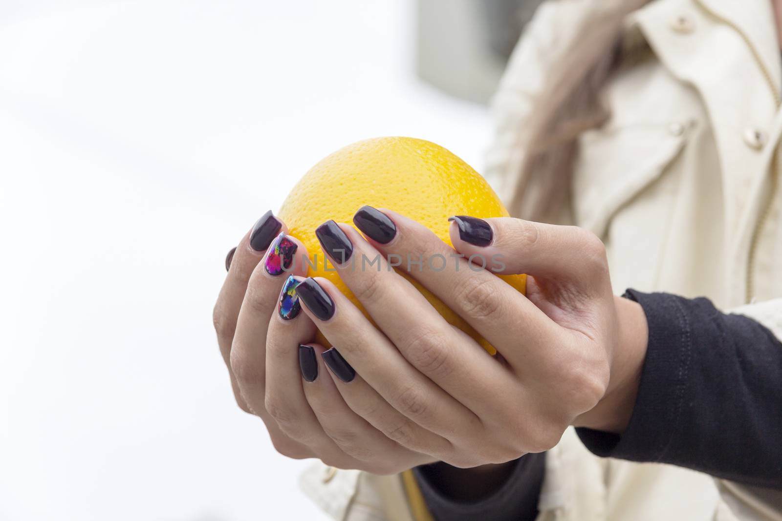 In the hands of a girl with a stylish manicure Orange bright orange