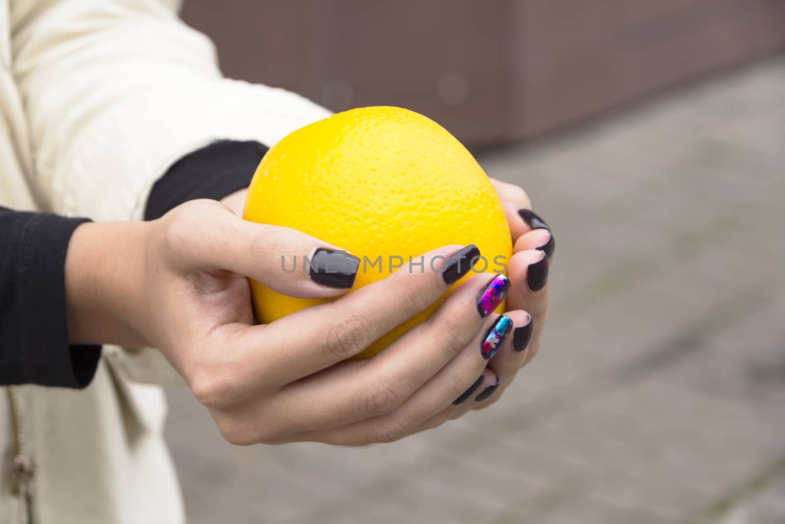 Hands girl with fashionable manicure keep oranges on the street