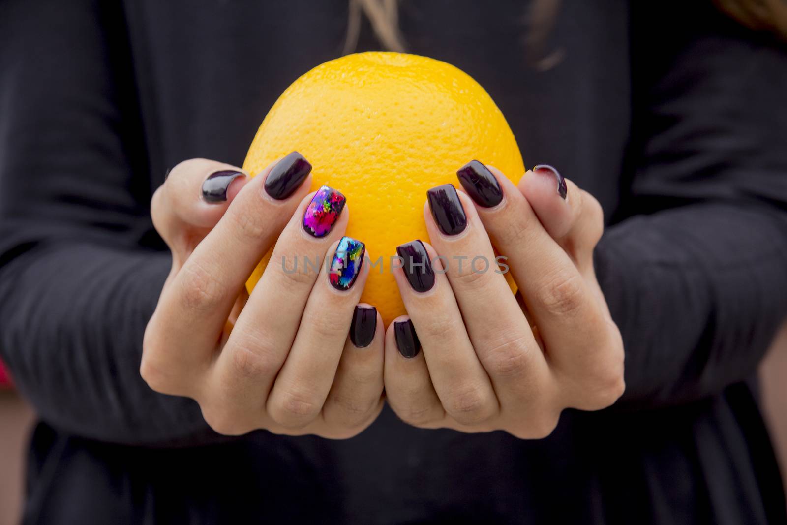 In the hands of a girl with a stylish manicure Orange bright orange