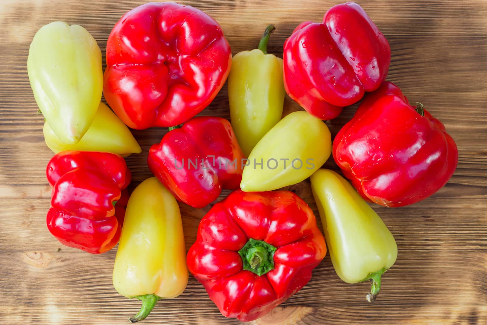 Vegetable still life of mature red and green peppers on wooden background