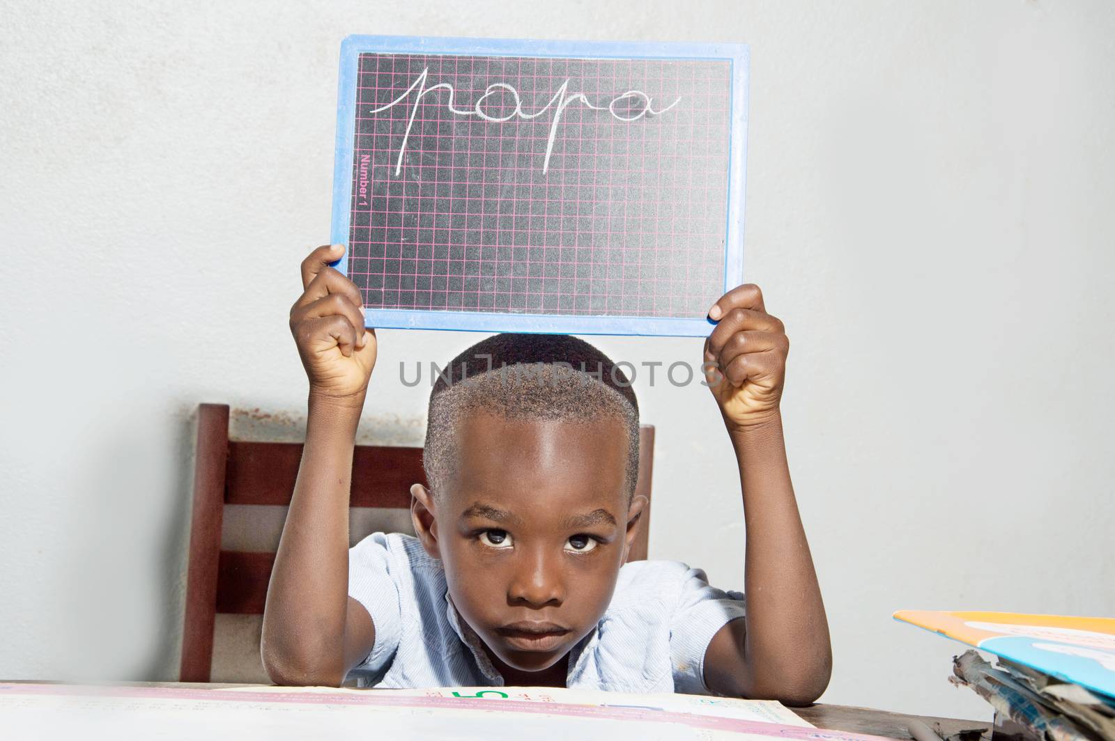 The child learns to write at home. He writes dad and shown to his mother.