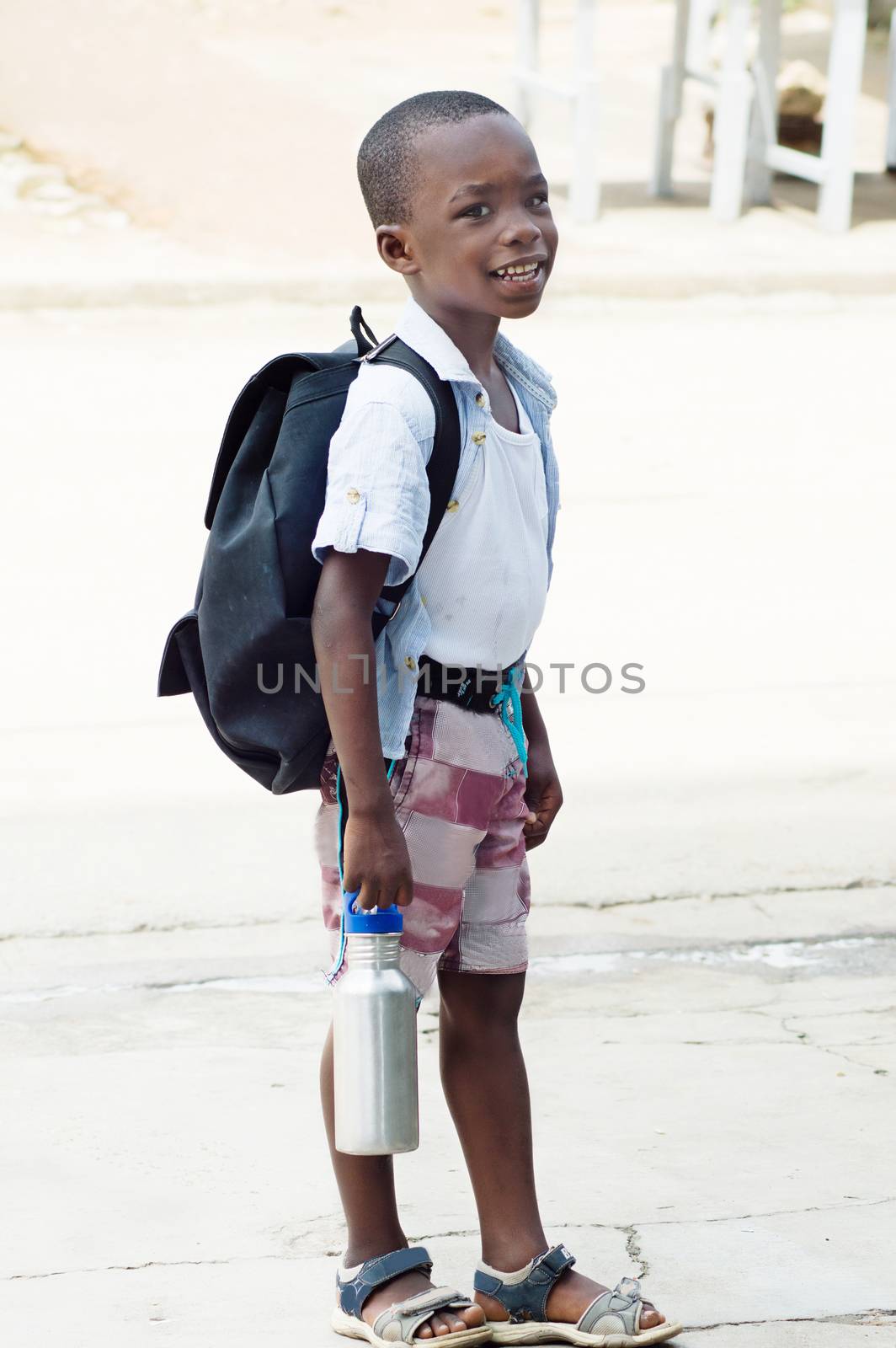 A small schoolboy waiting for a school bus.