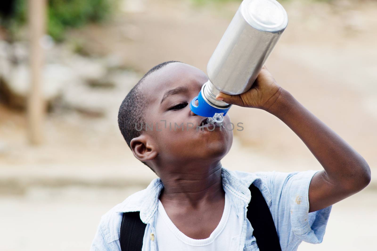 This child is drinking water on the way to school.