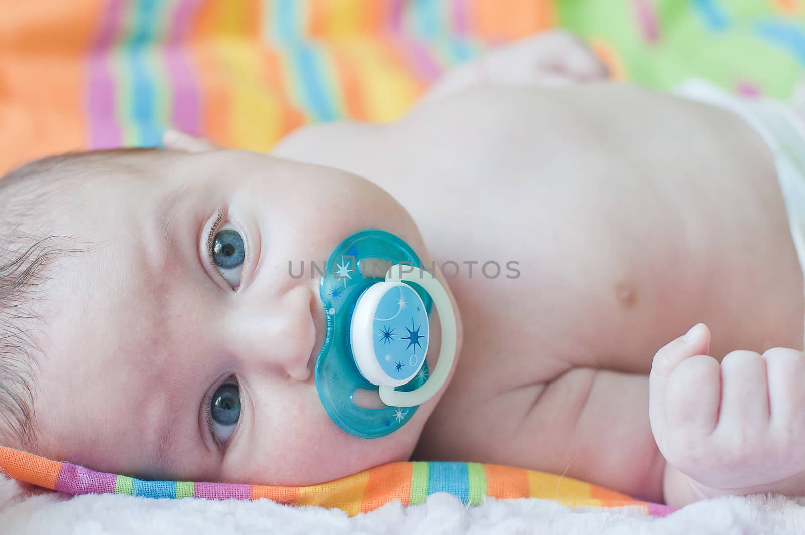 Little baby with blue soother lays