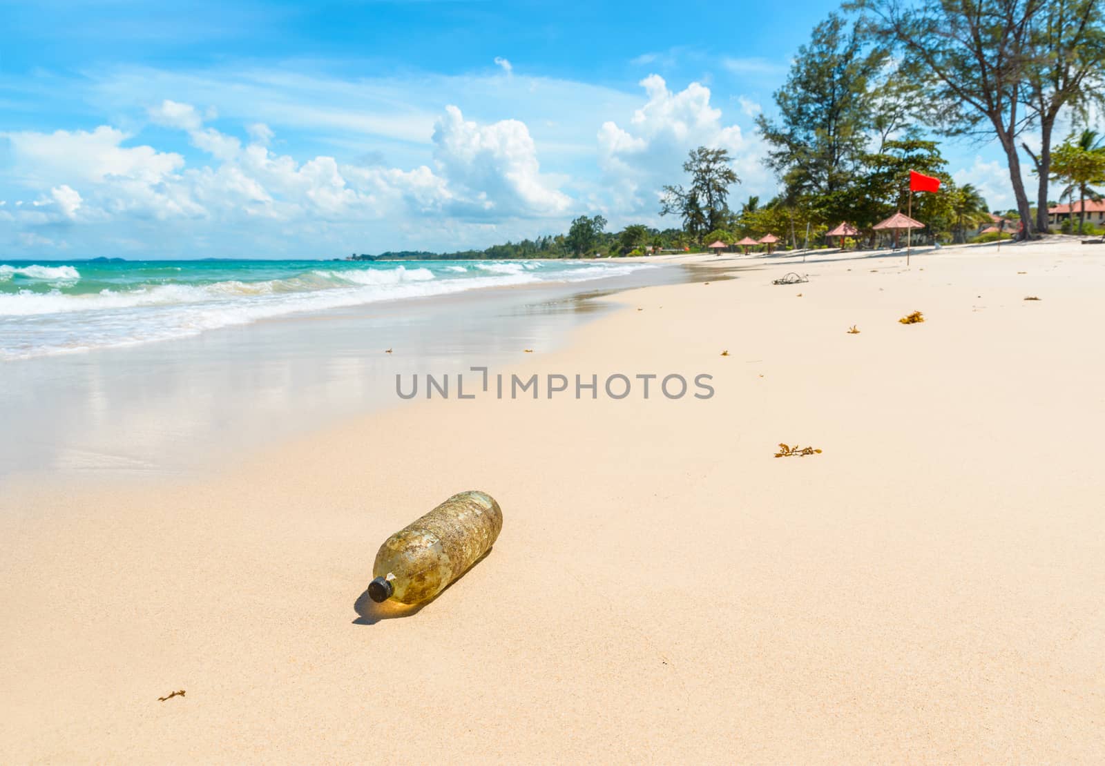 Old plastic bottle on a beautiful tropical beach in Indonesia. Pollution concept.