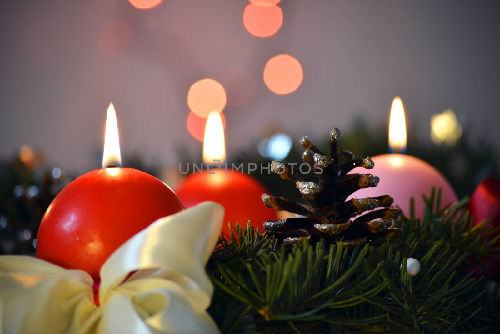 Three Advent Candles against Christmas tree and decorated on the table, in the night time