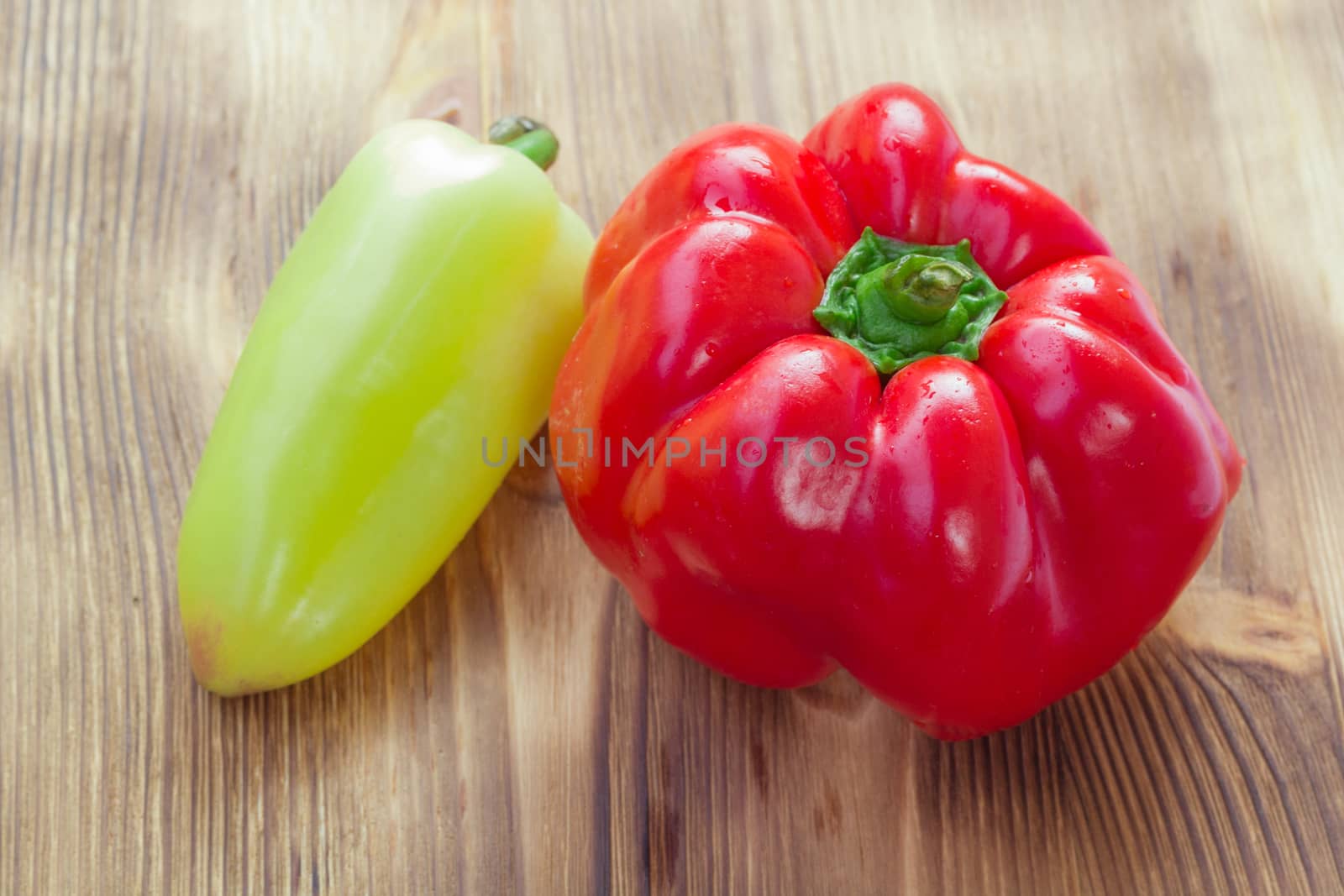 Vegetable still life of two mature red and green peppers on wooden background