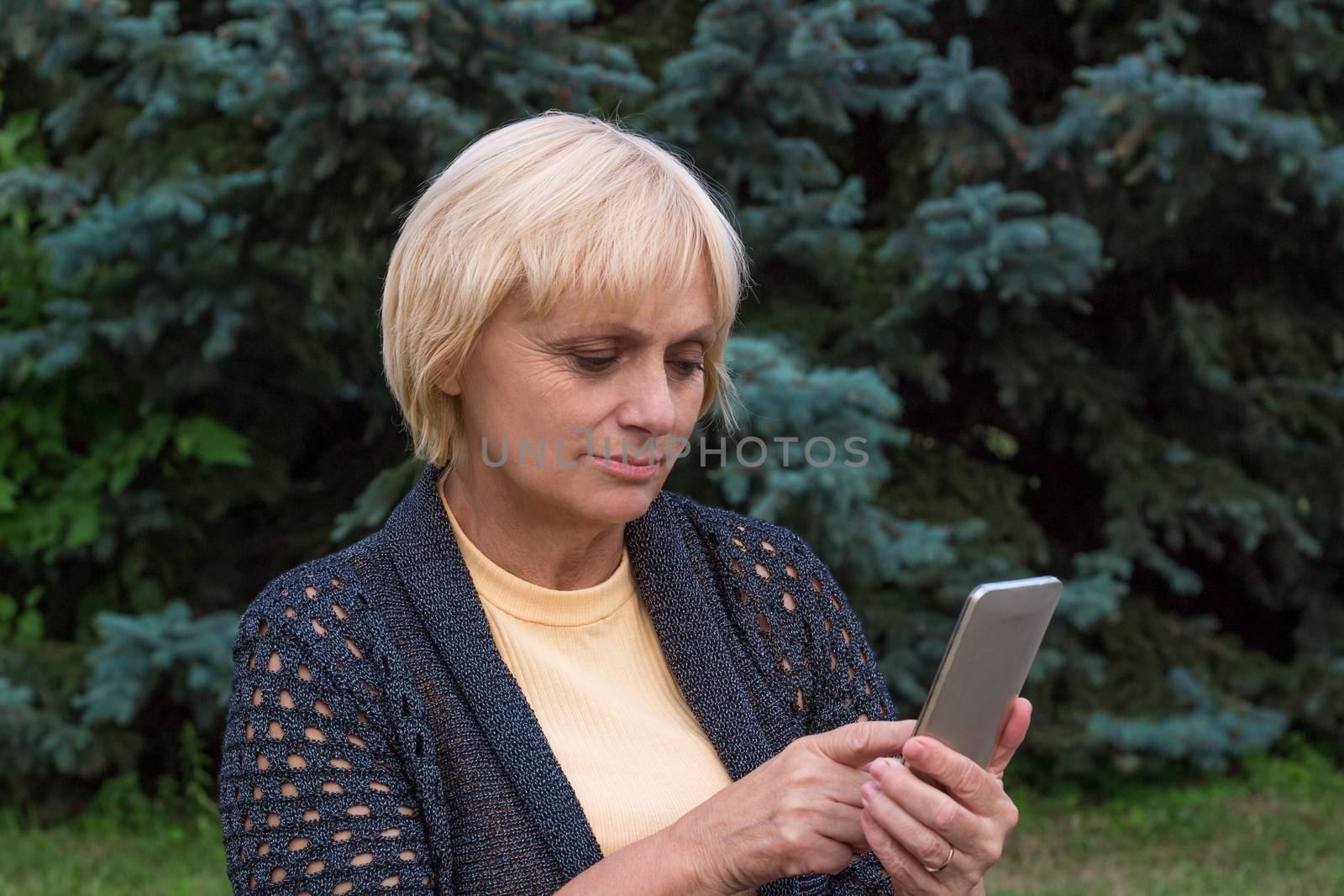 Elderly woman dials or texts on mobile cellar phone