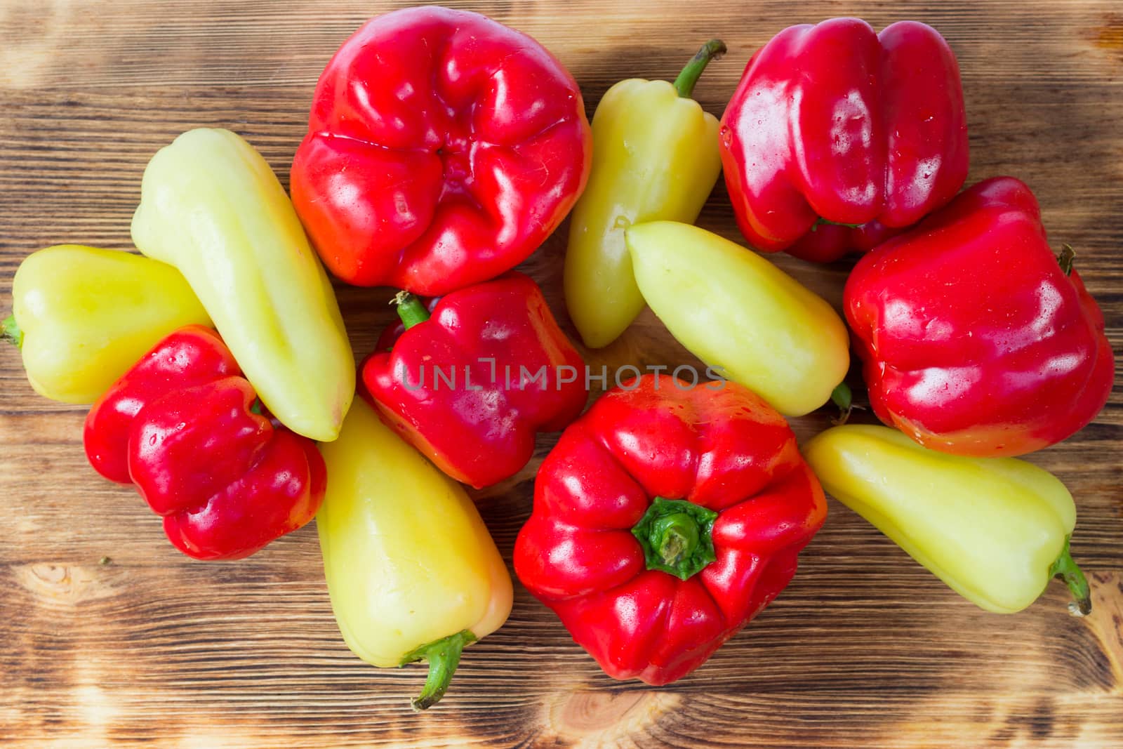 Vegetable still life of mature red and green peppers on wooden background