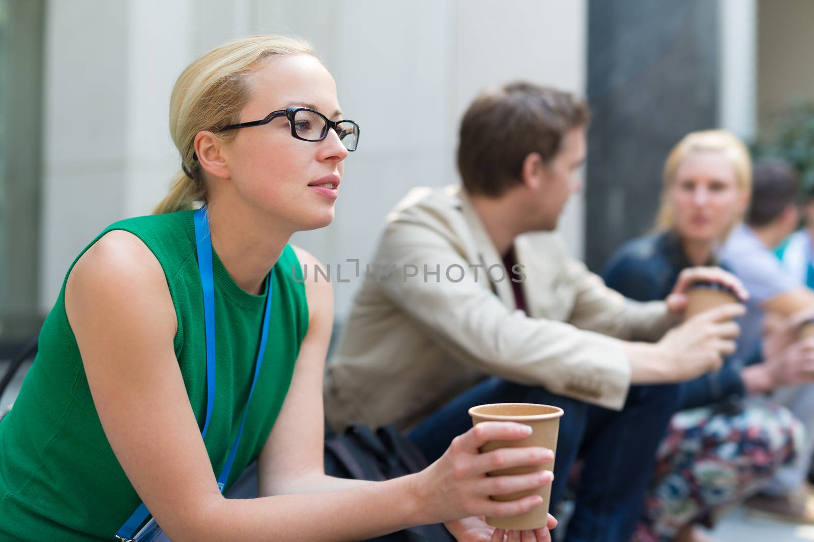 Cheerful colleagues meeting on stairs outdoor for in a quick coffee break. Coffee to go.
