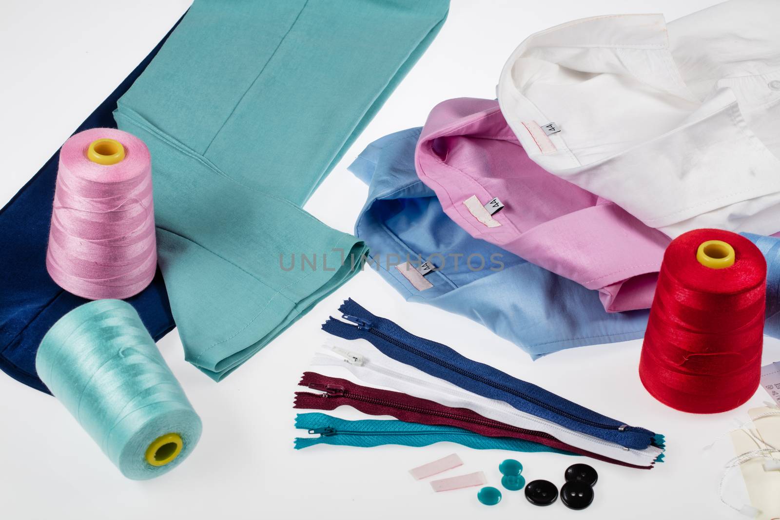 Different tailor's accessories, pants and shirts on a studio background