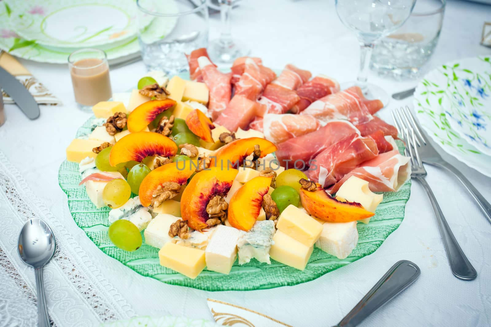 Cocktail food appetizer with ham rollspeaches, grapes, wallnuta and a variety os cheeses