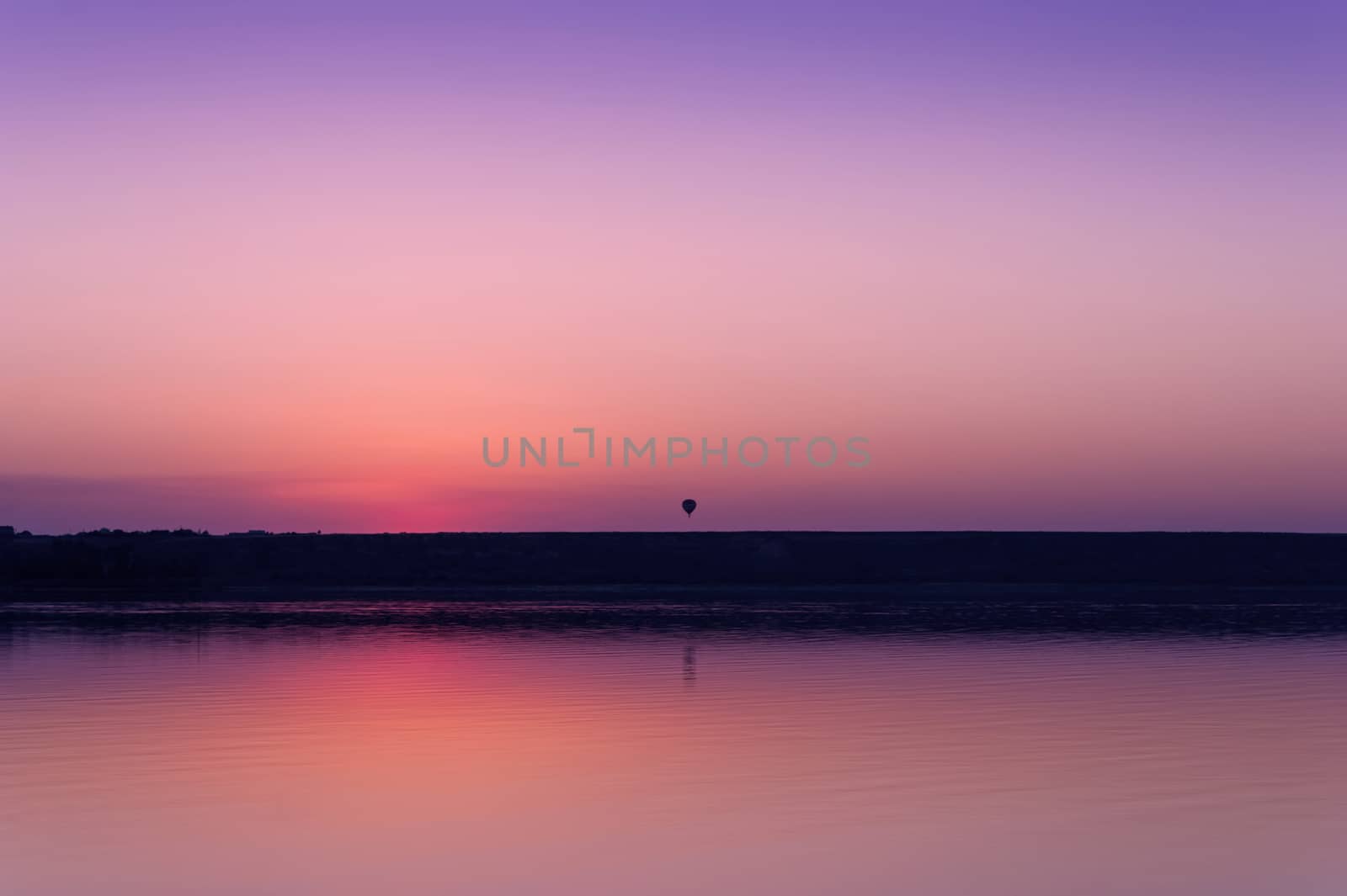 Colorful bright orange red summer sunset over lake and a balloon on a background