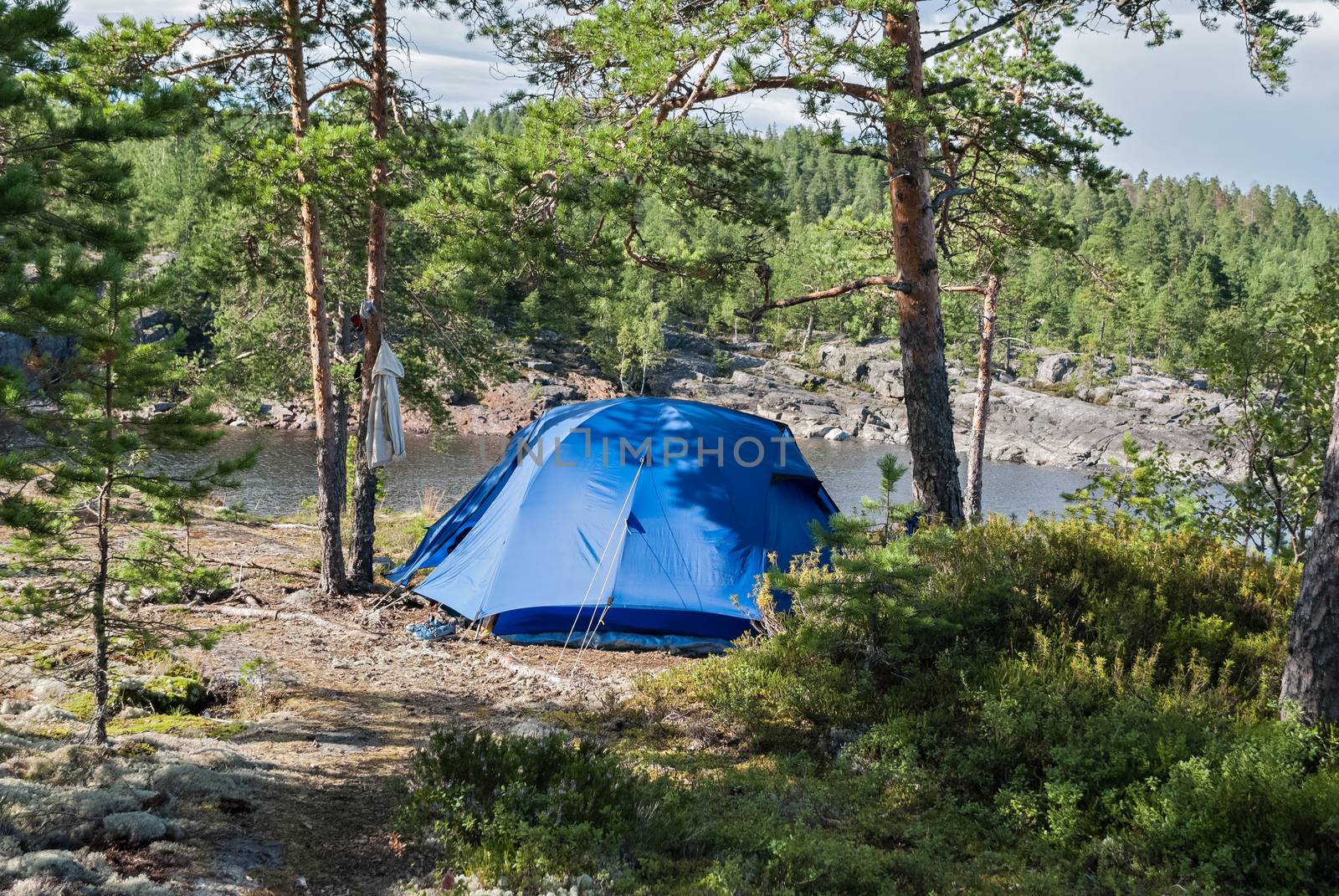 Blue tourist tent on the rocky shore of Lake Ladoga in Karelia.