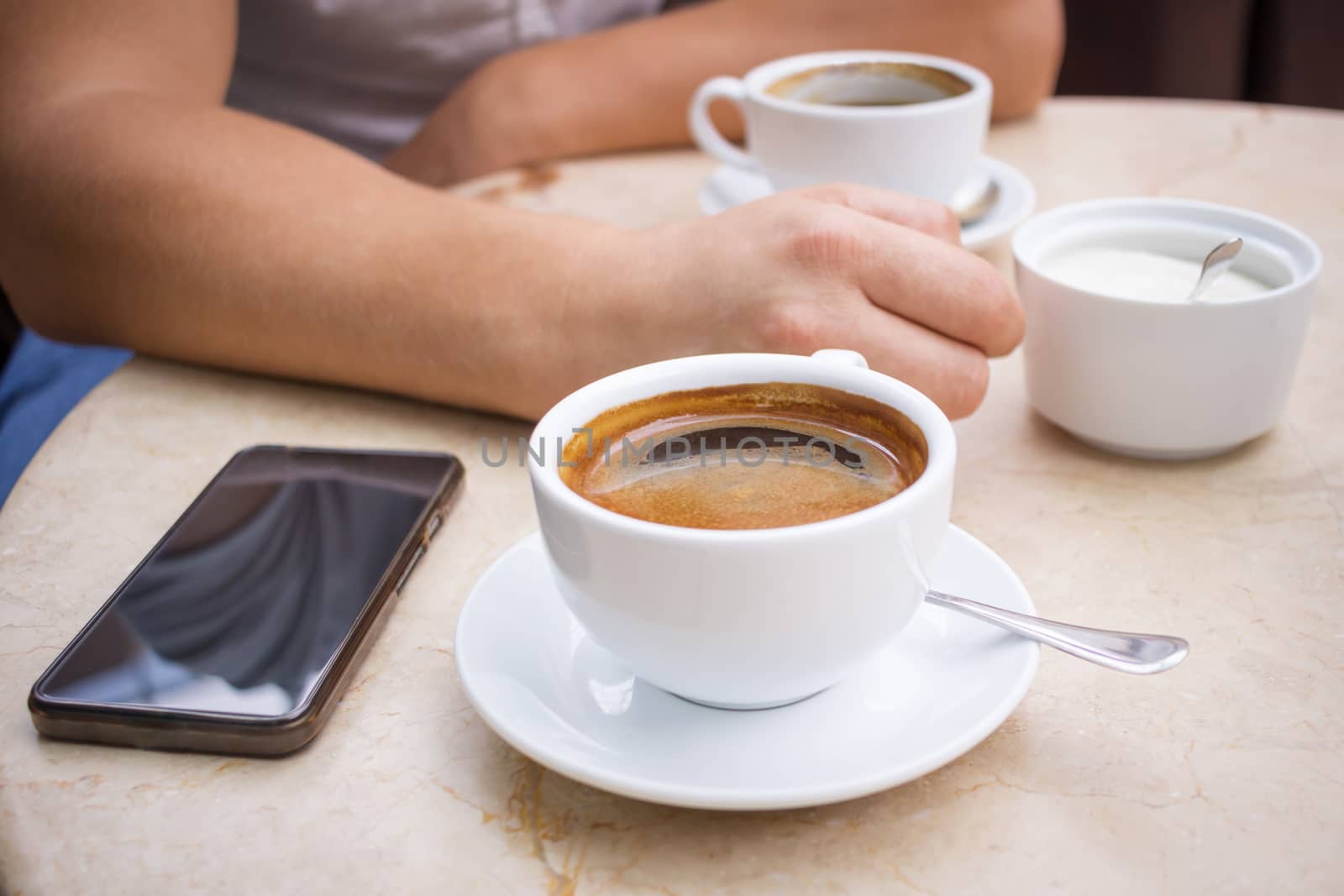 Man sits at marble table with smartphone and cup of coffee