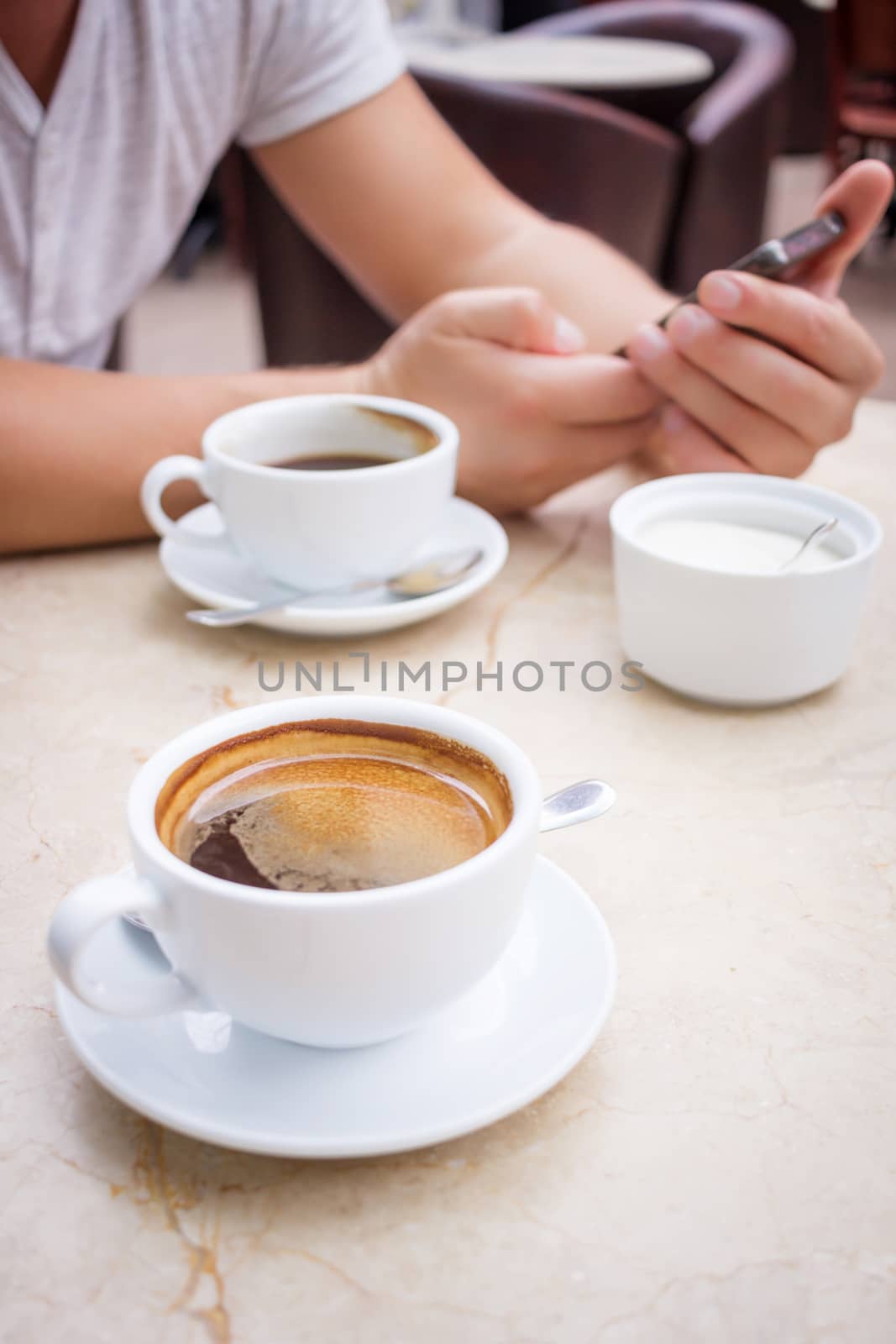 Man sits with smartphone at marble table with cup of coffee