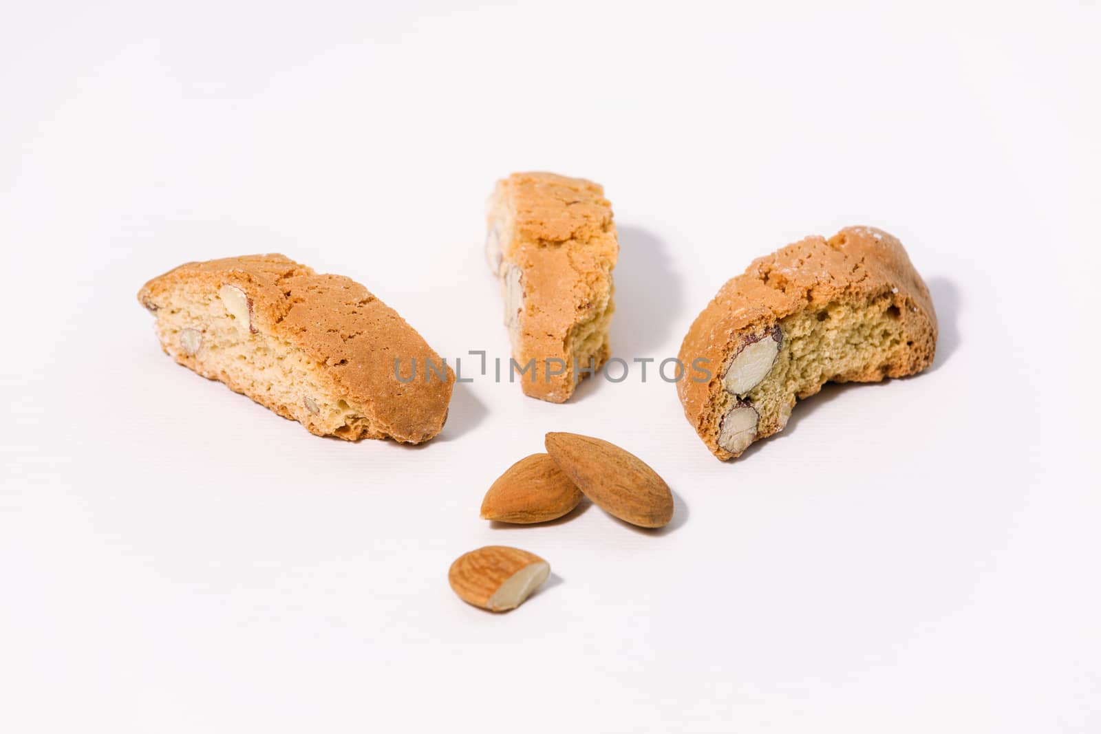 Three almond cantuccini and three almonds on white background
