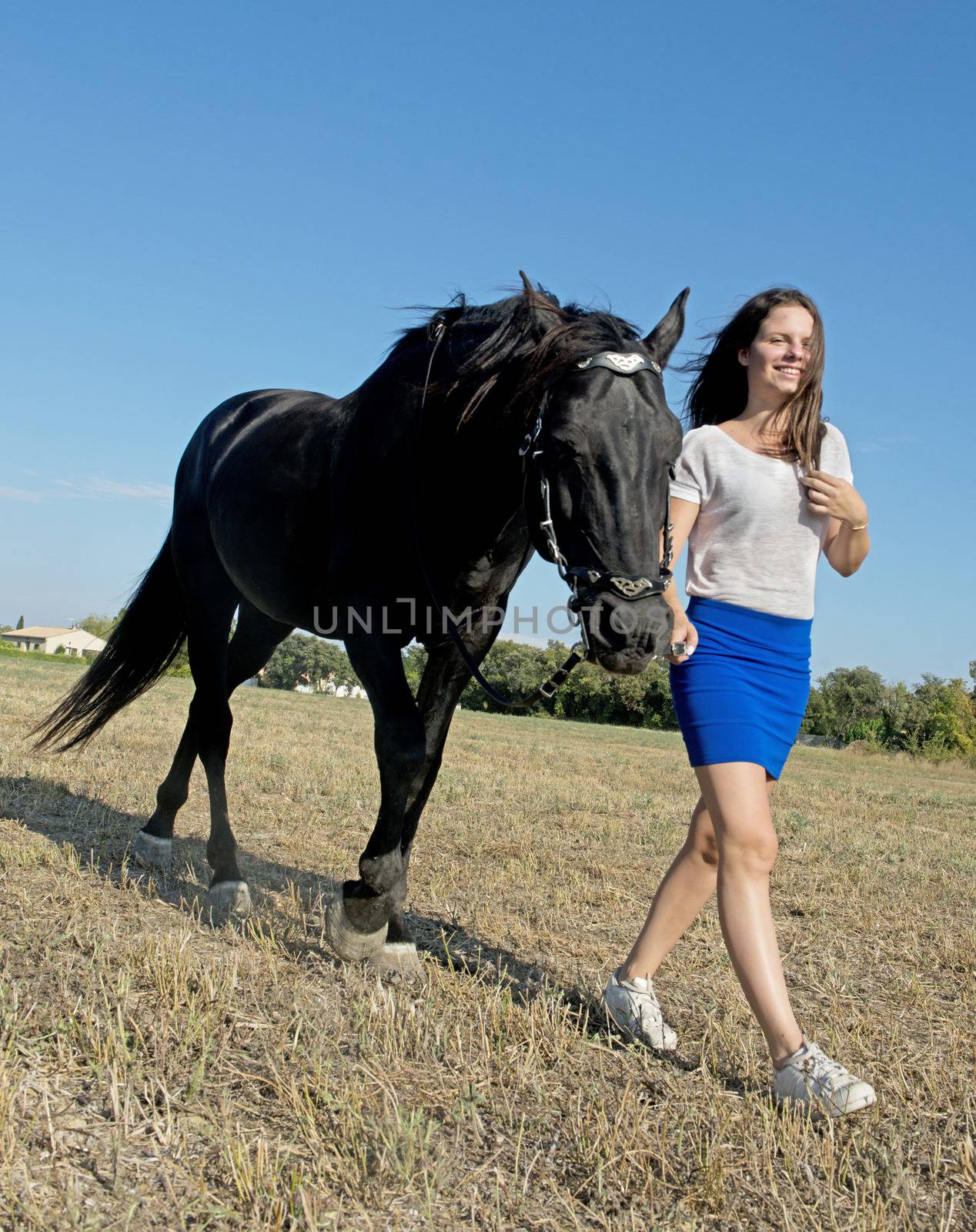 young girl riding a black stallion in a field