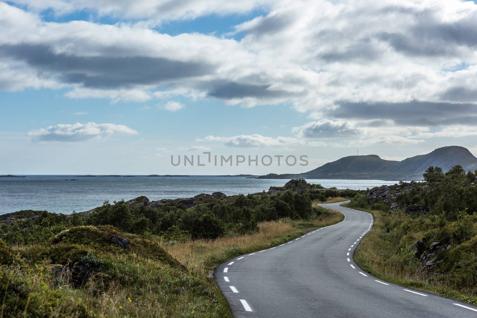 Road in Norway, Lofoten leading into mountains and around the coast.