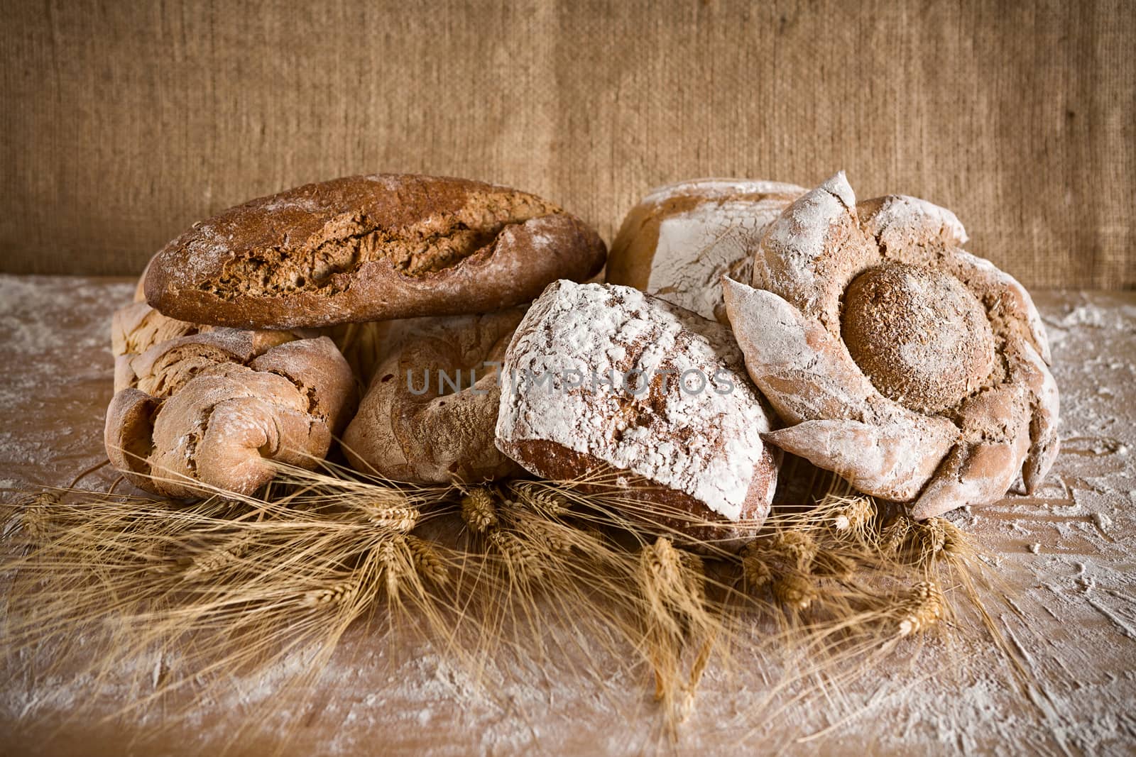 Bread of various types with sheaves of wheat and jute background
