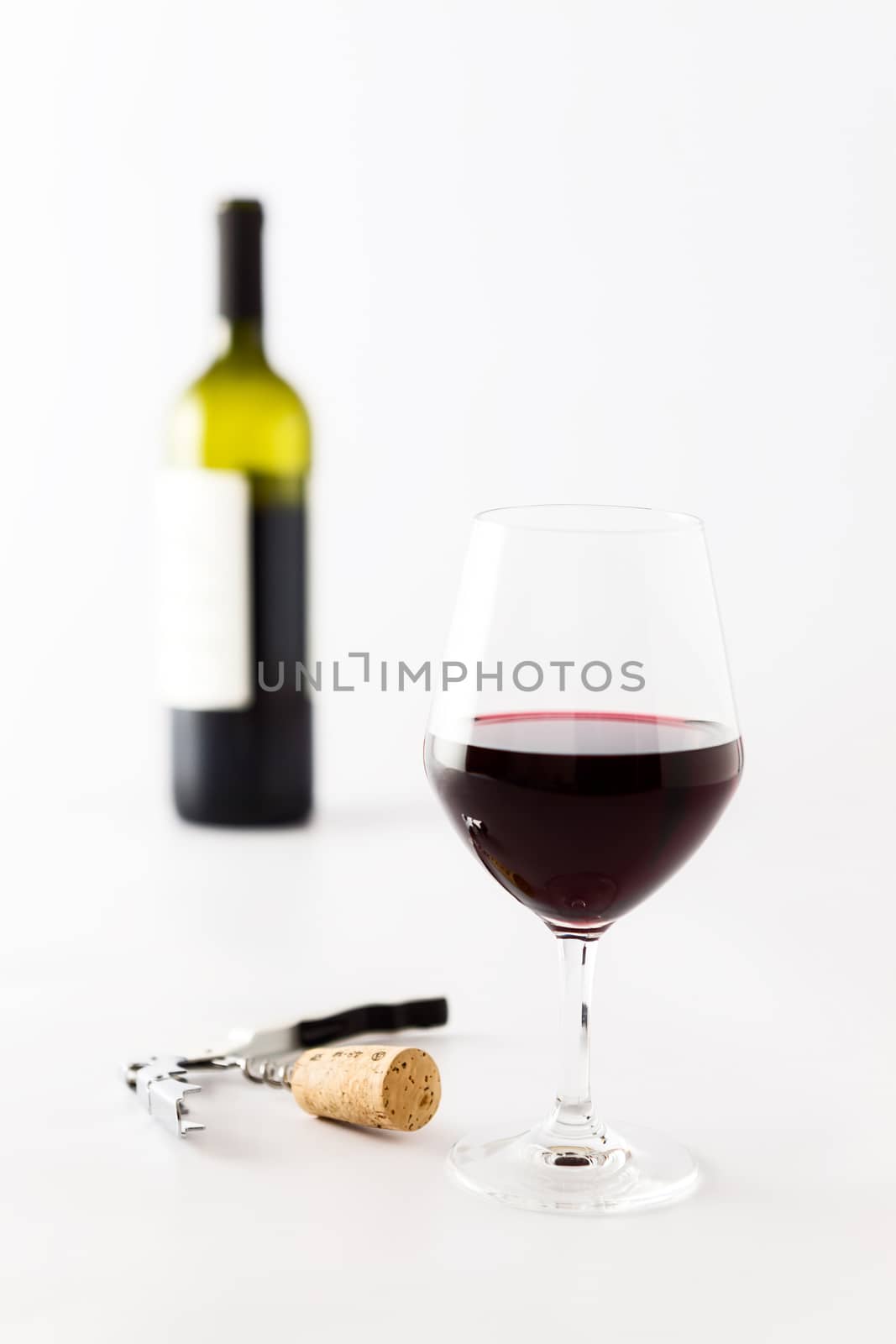 Glass of red wine and bottle on background, cork and corkscrew on a white background