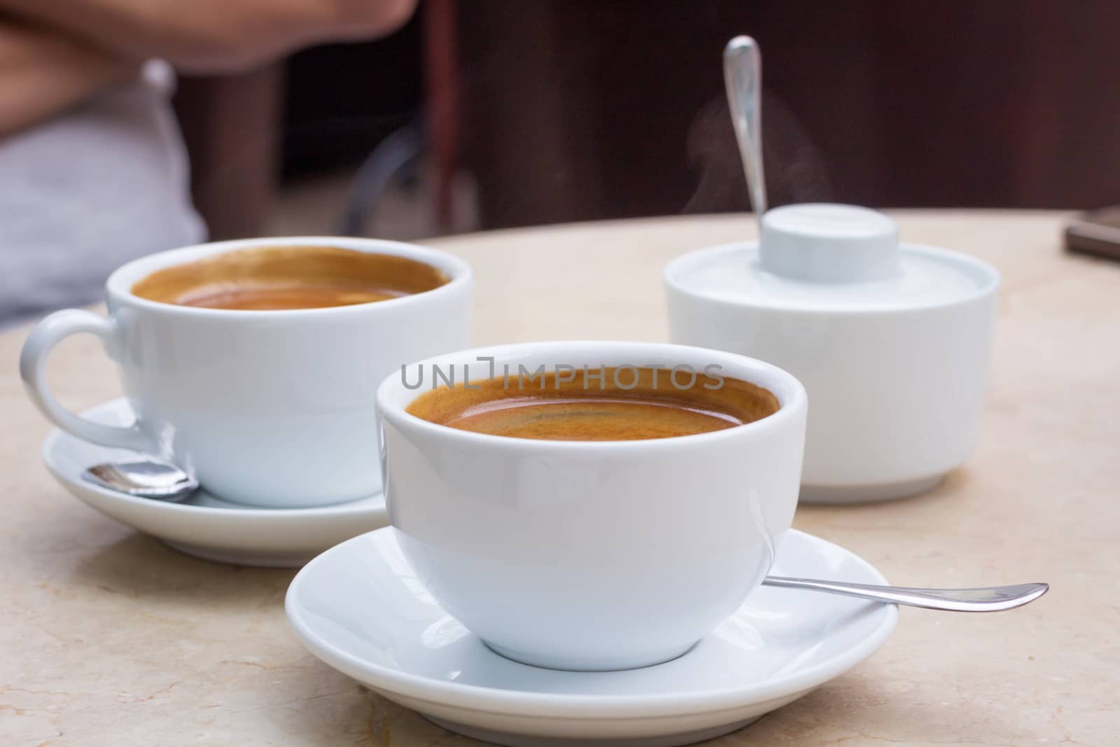 Coffee break in cafe, two cups of coffee and sugar bowl on marble table top