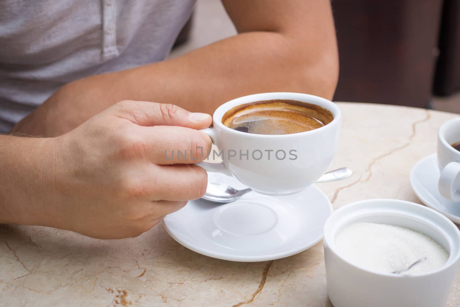 Man at marble table holds a cup of americano coffee in his hand