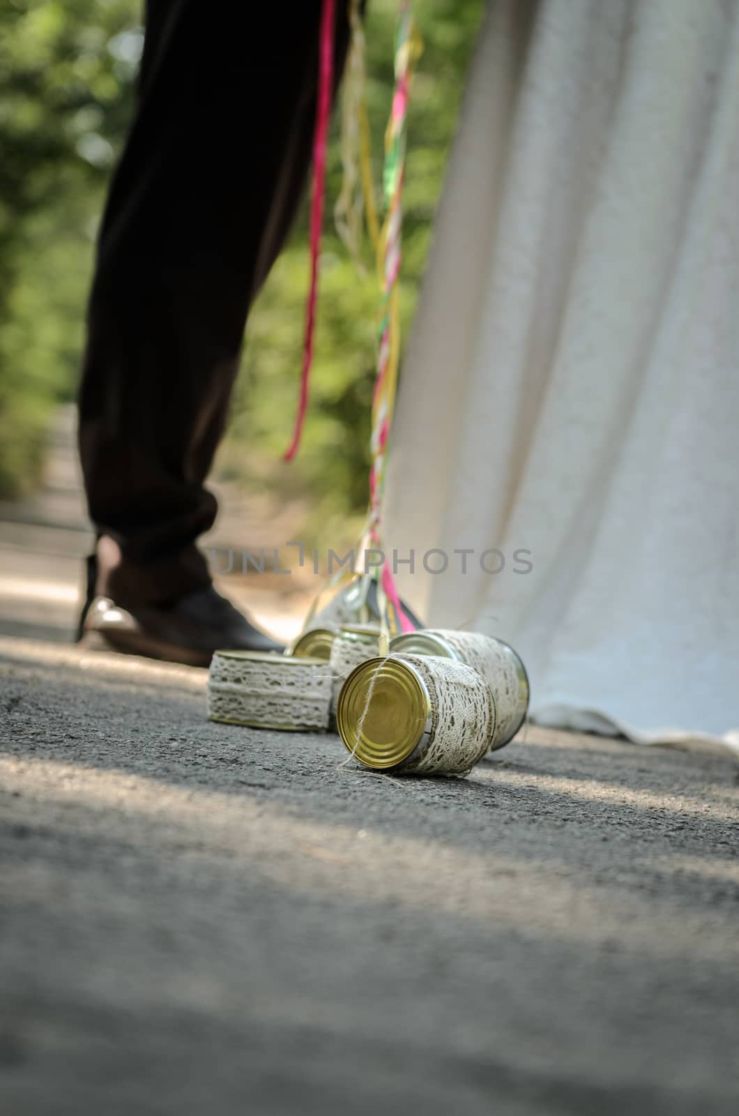 tin cans tied with ribbons, the bride and groom are holding the ribbon