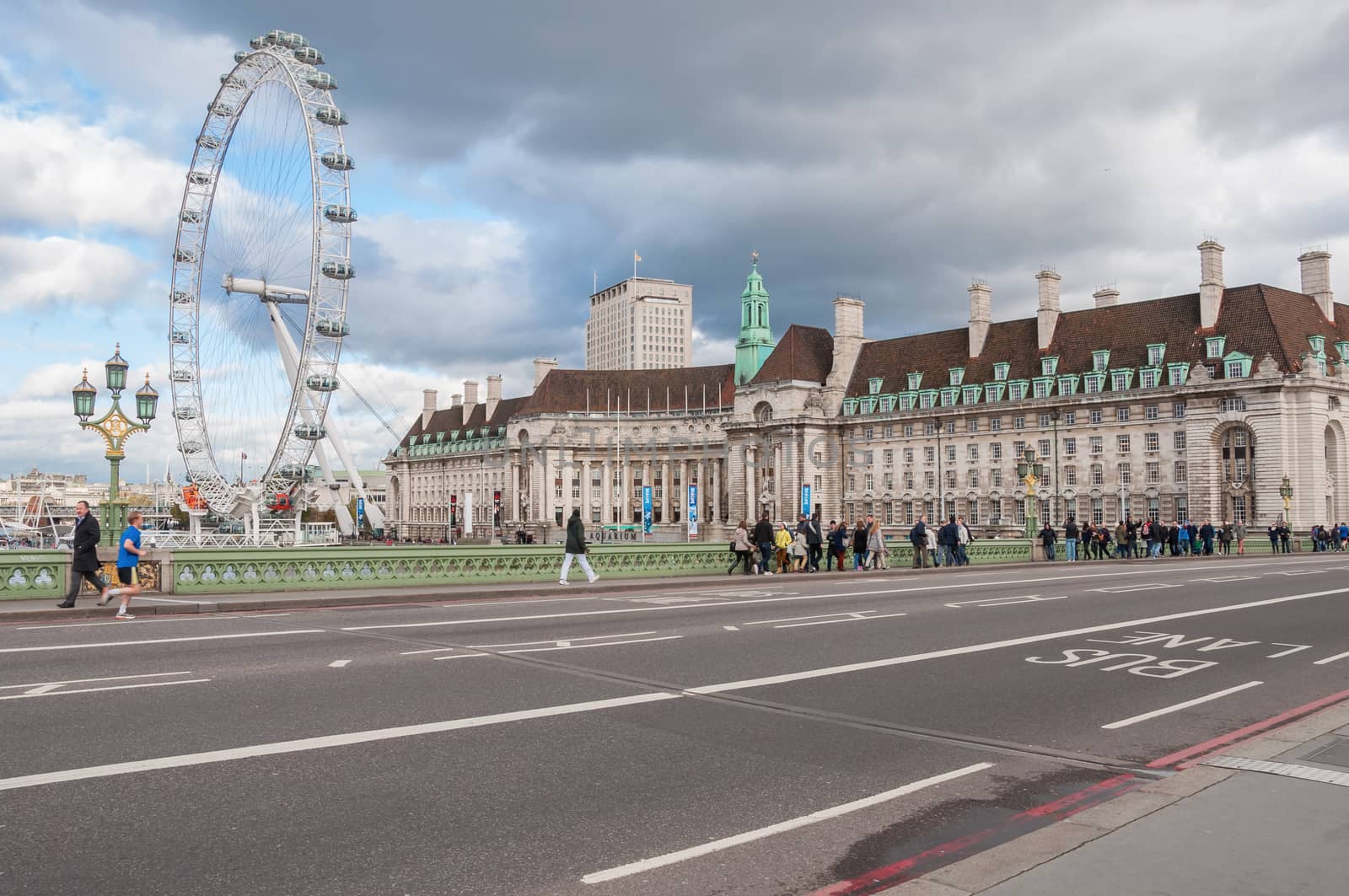 LONDON, UNITED KINGDOM - NOVEMBER 7, 2014: People cross the Westminster Bridge in front of the London Eye and County Hall, famous landmarks of London.