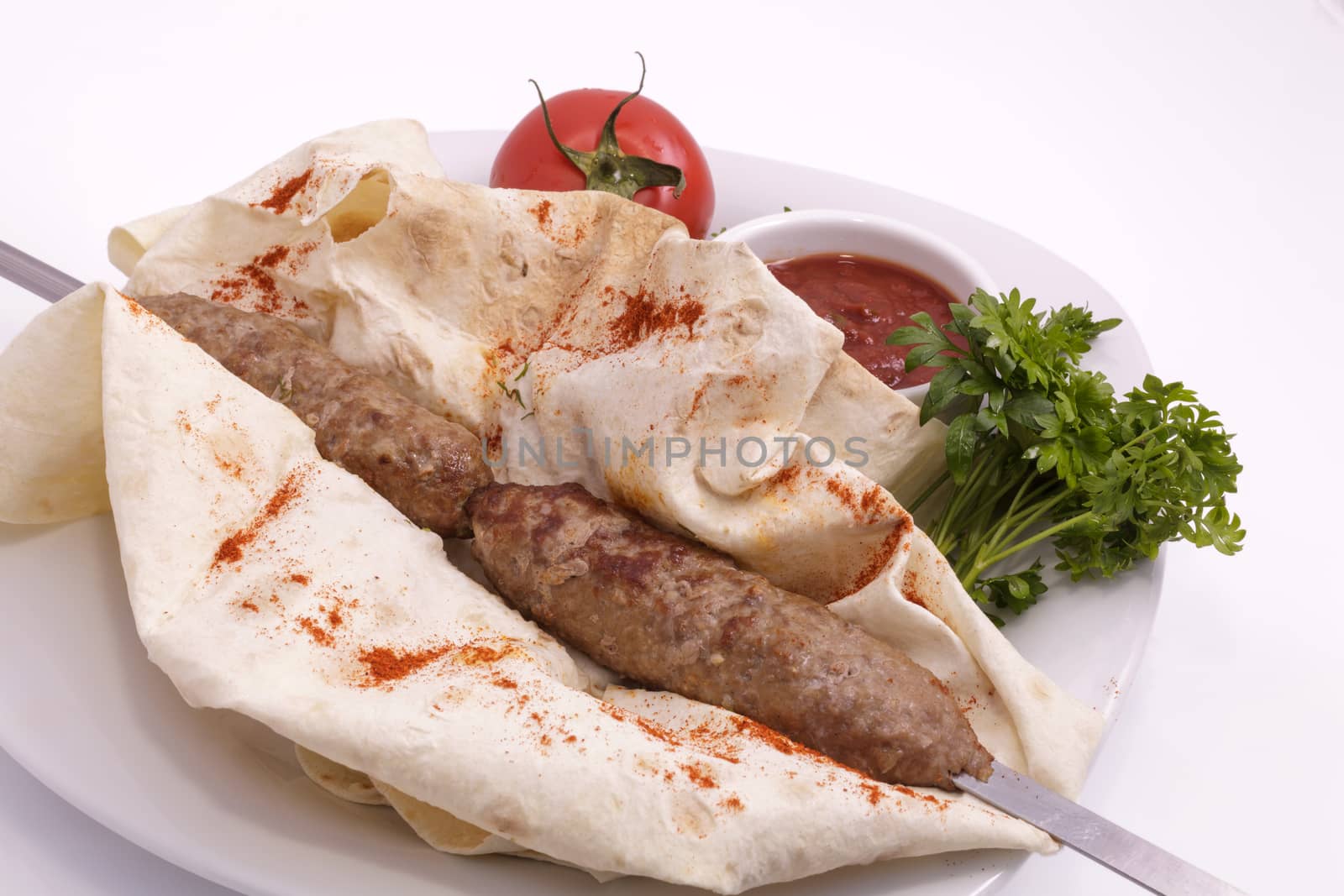 shashlik on a plate with sauce, onions and pita