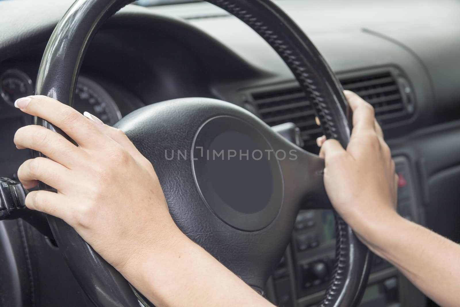 Arm girls with trendy manicure holds the steering wheel in the car.