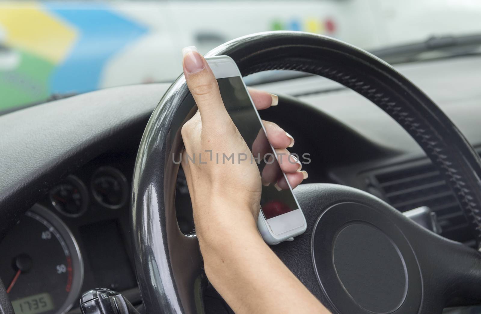 girl with a mobile phone behind the wheel in the saloon car