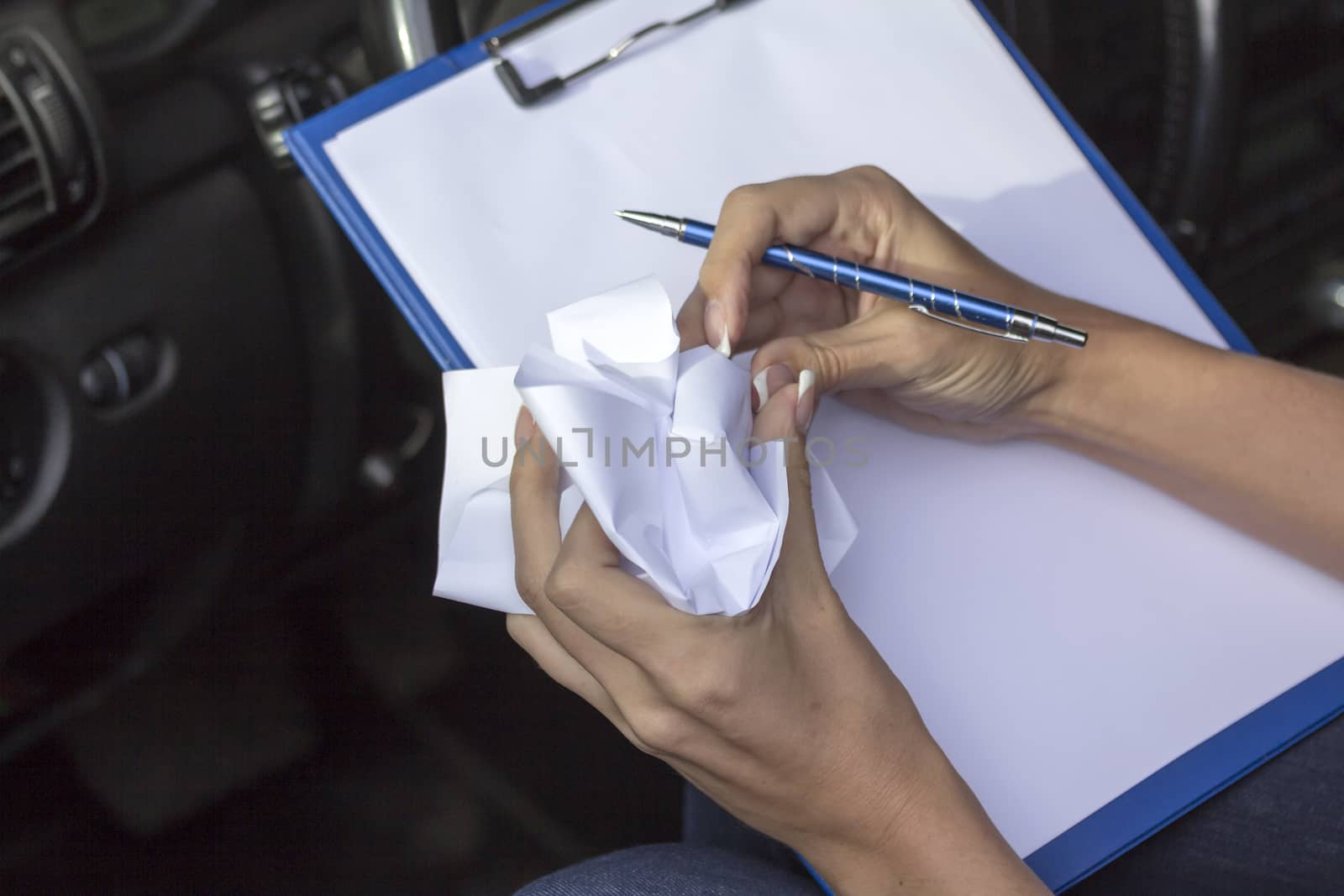 Girl in car holds clip board, pen and paper jammed