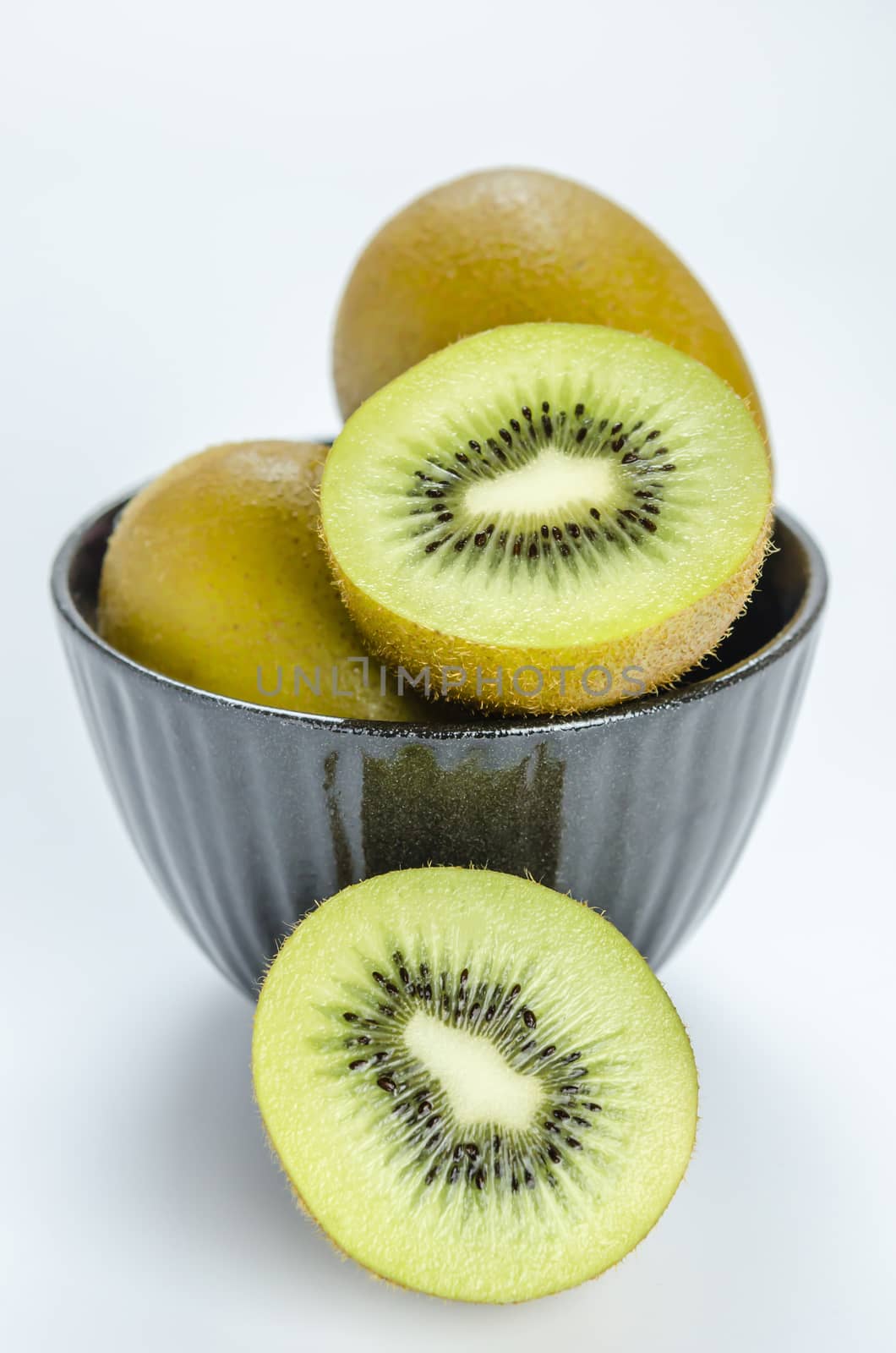 kiwi fruit and half with black bowl on white background
