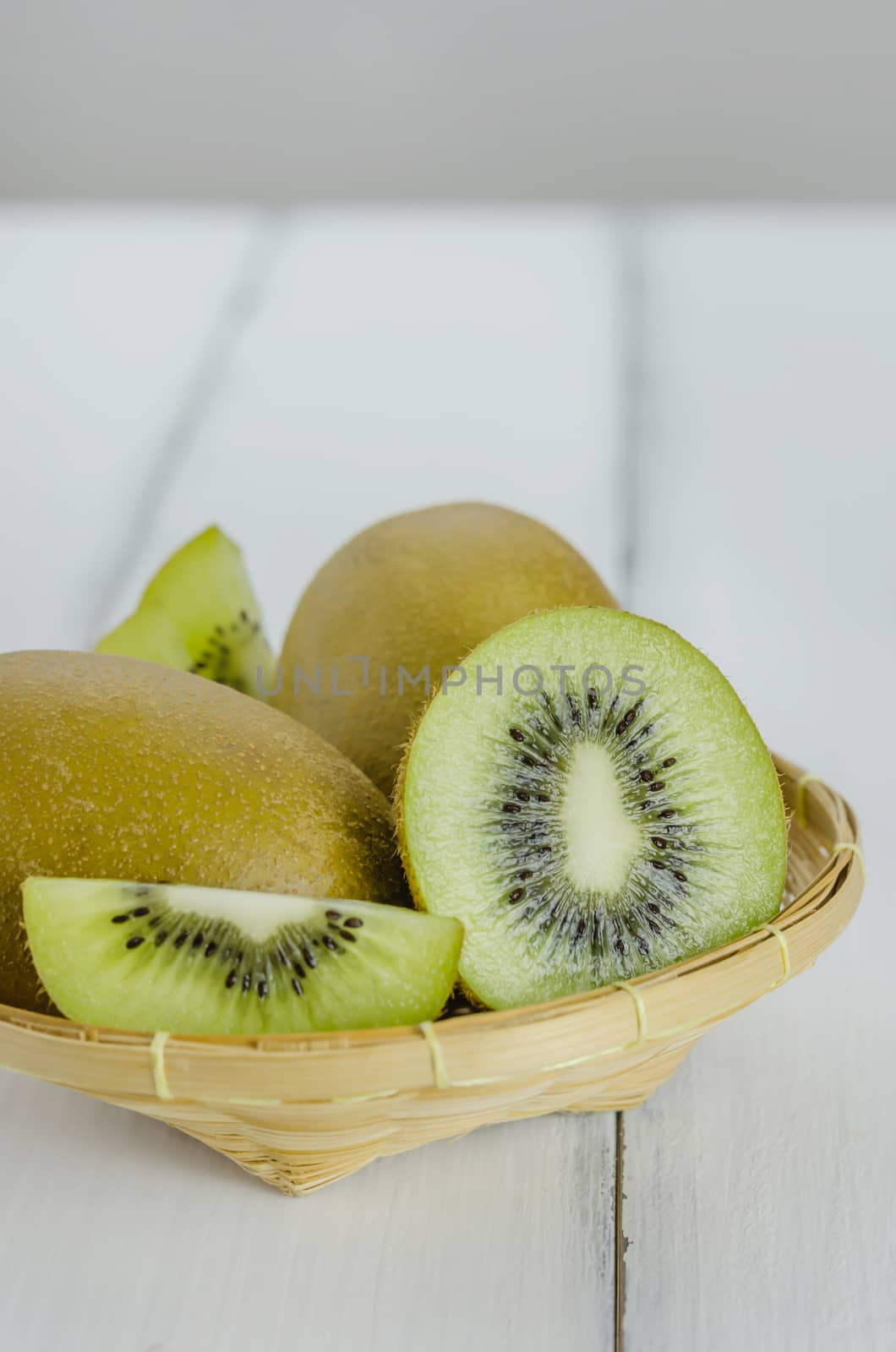 kiwi fruit and sliced with bamboo basket on wooden background