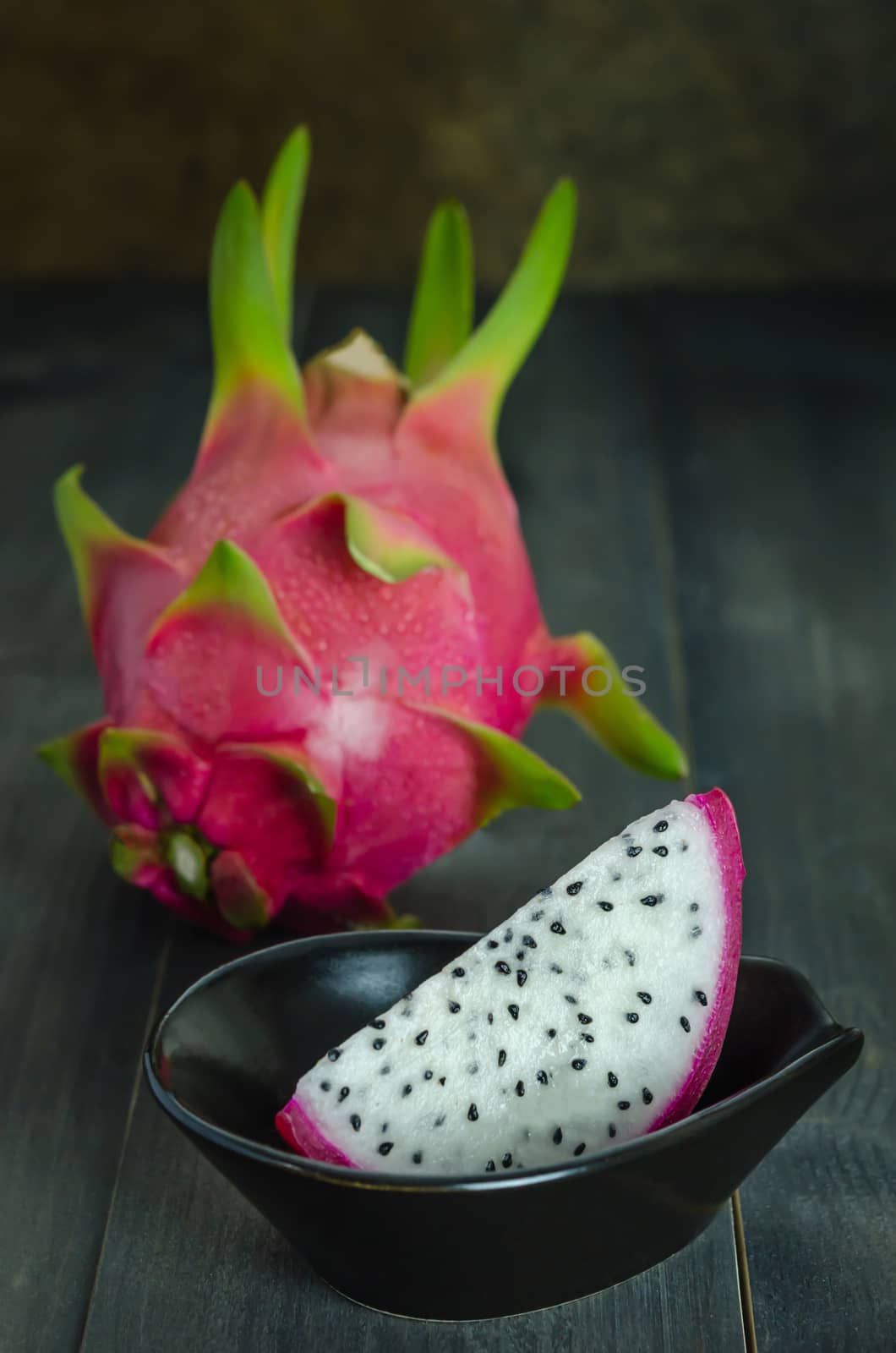 Ripe Dragon fruit  with slice in bowl over wooden background , still life