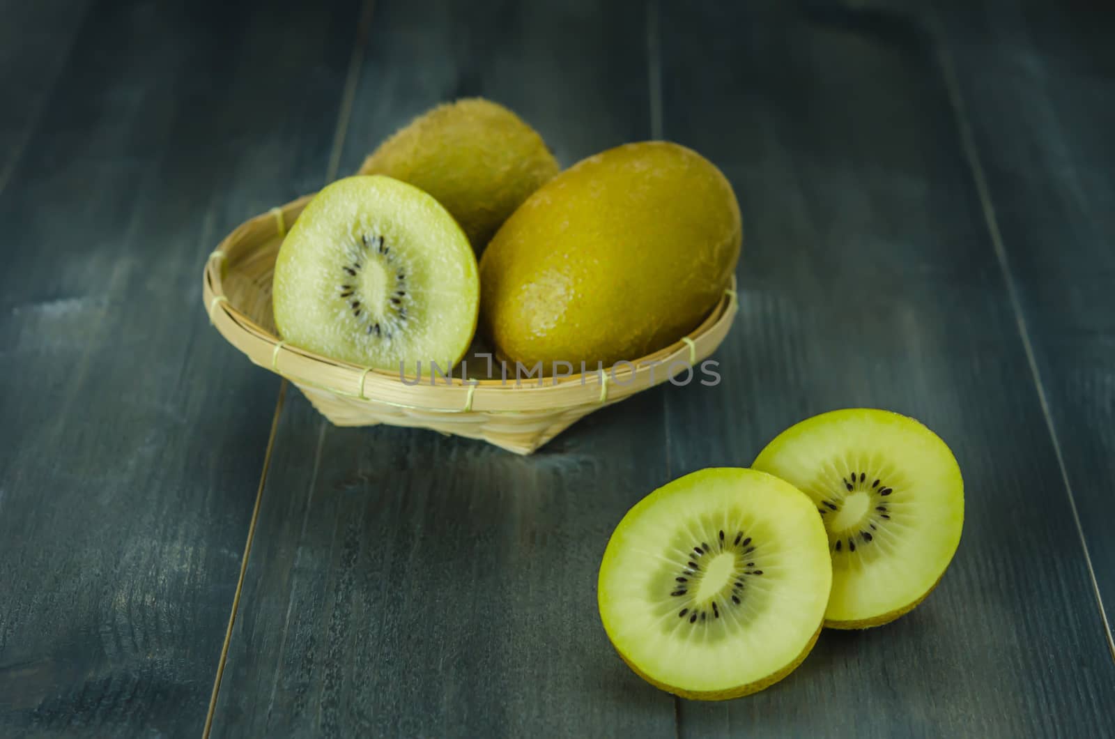 kiwi fruit and sliced with bamboo basket on wooden background , still life