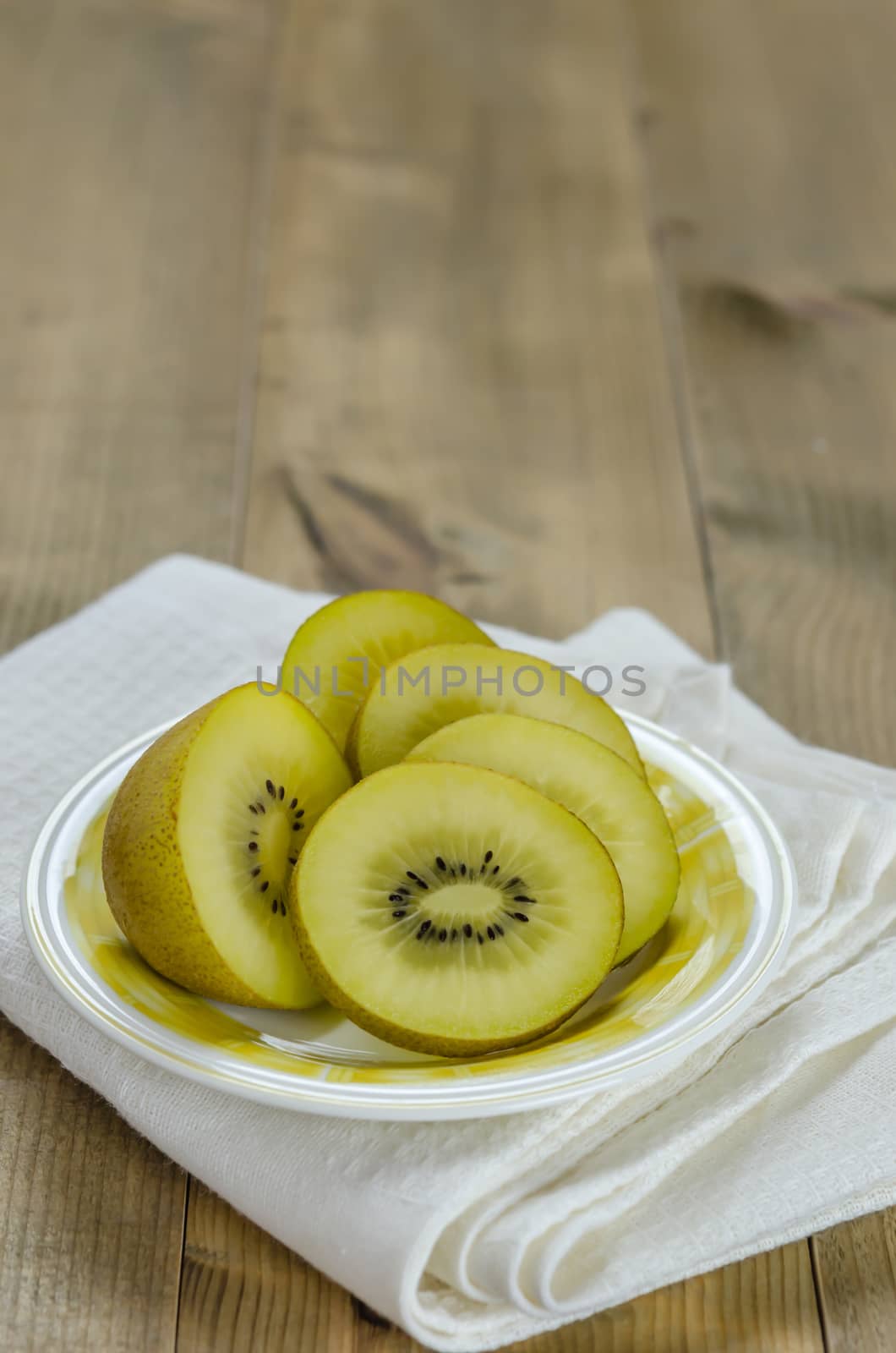 golden kiwi fruit and sliced on dish over wooden background