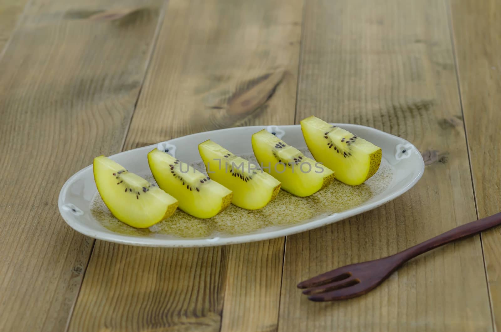 sliced of golden kiwi fruit  on dish over wooden background