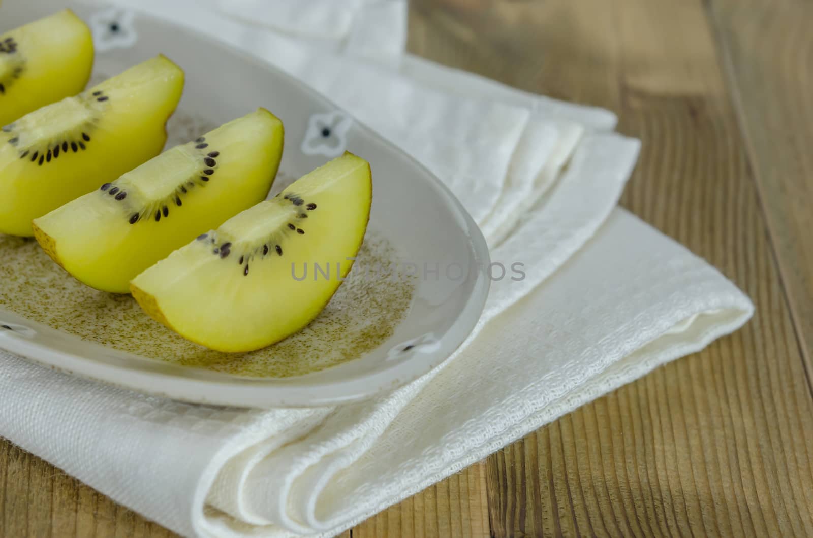 sliced of golden kiwi fruit  on dish over wooden background