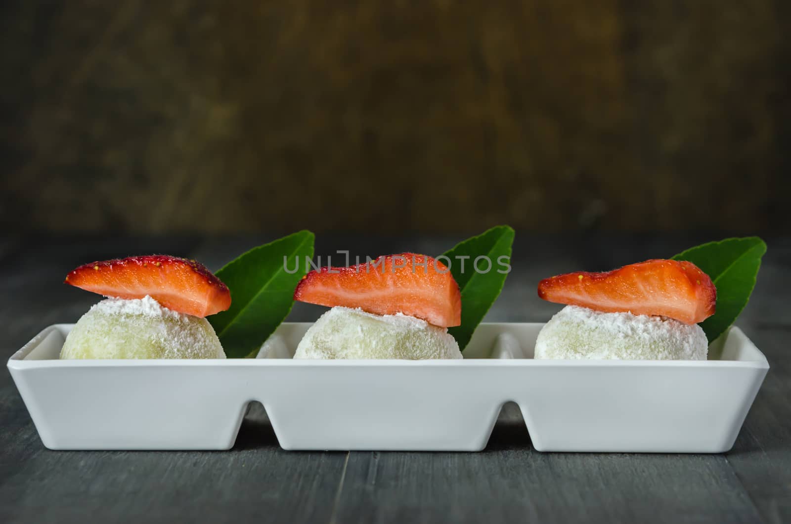 Strawberry Daifuku Mochi Japanese dessert on white plate over wooden background, still life
