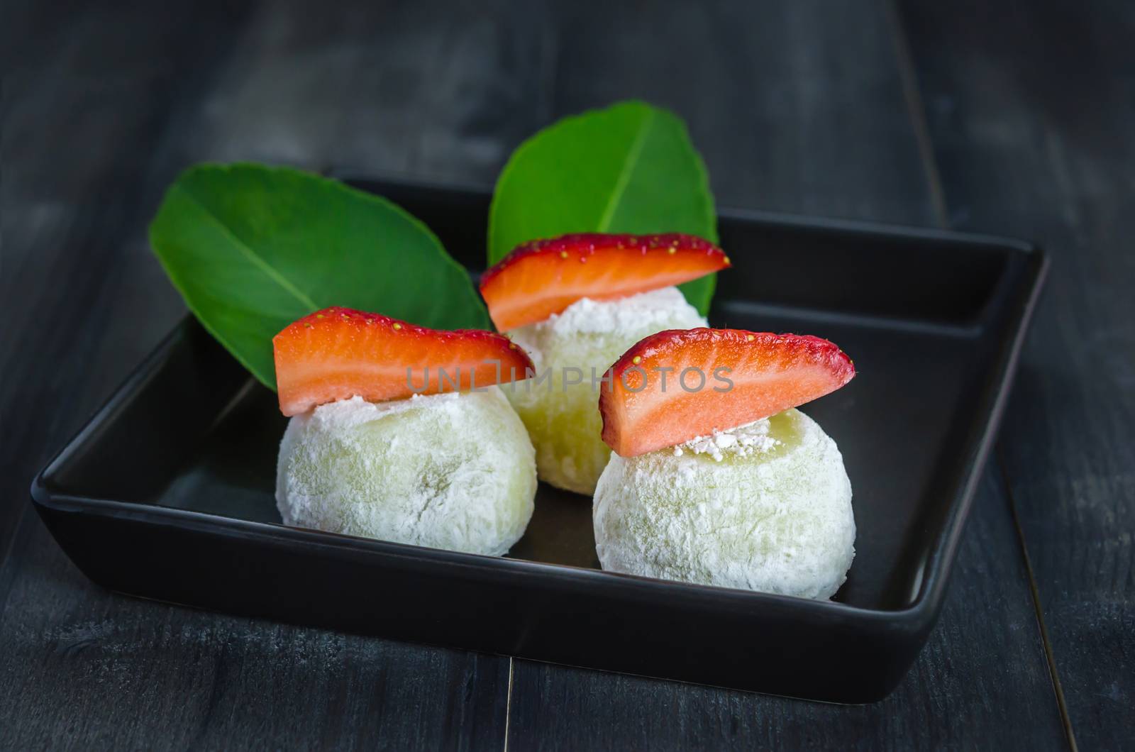 Strawberry Daifuku Mochi Japanese dessert on black dish over wooden background