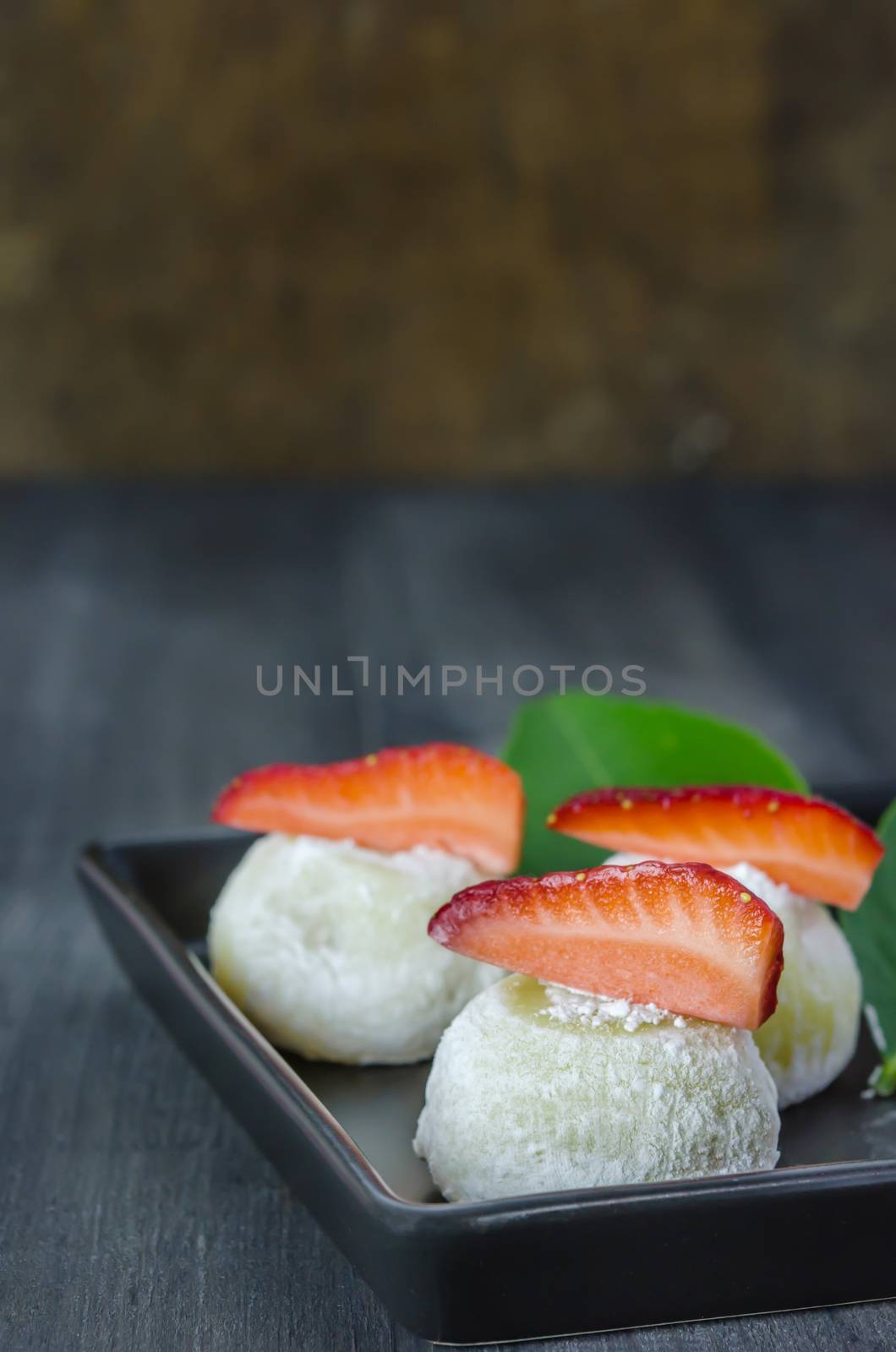 Strawberry Daifuku Mochi Japanese dessert on black dish over wooden background