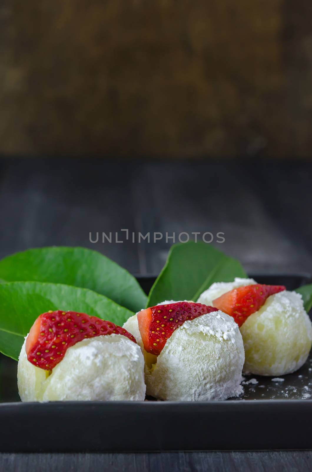 Strawberry Daifuku Mochi Japanese dessert on black dish over wooden background