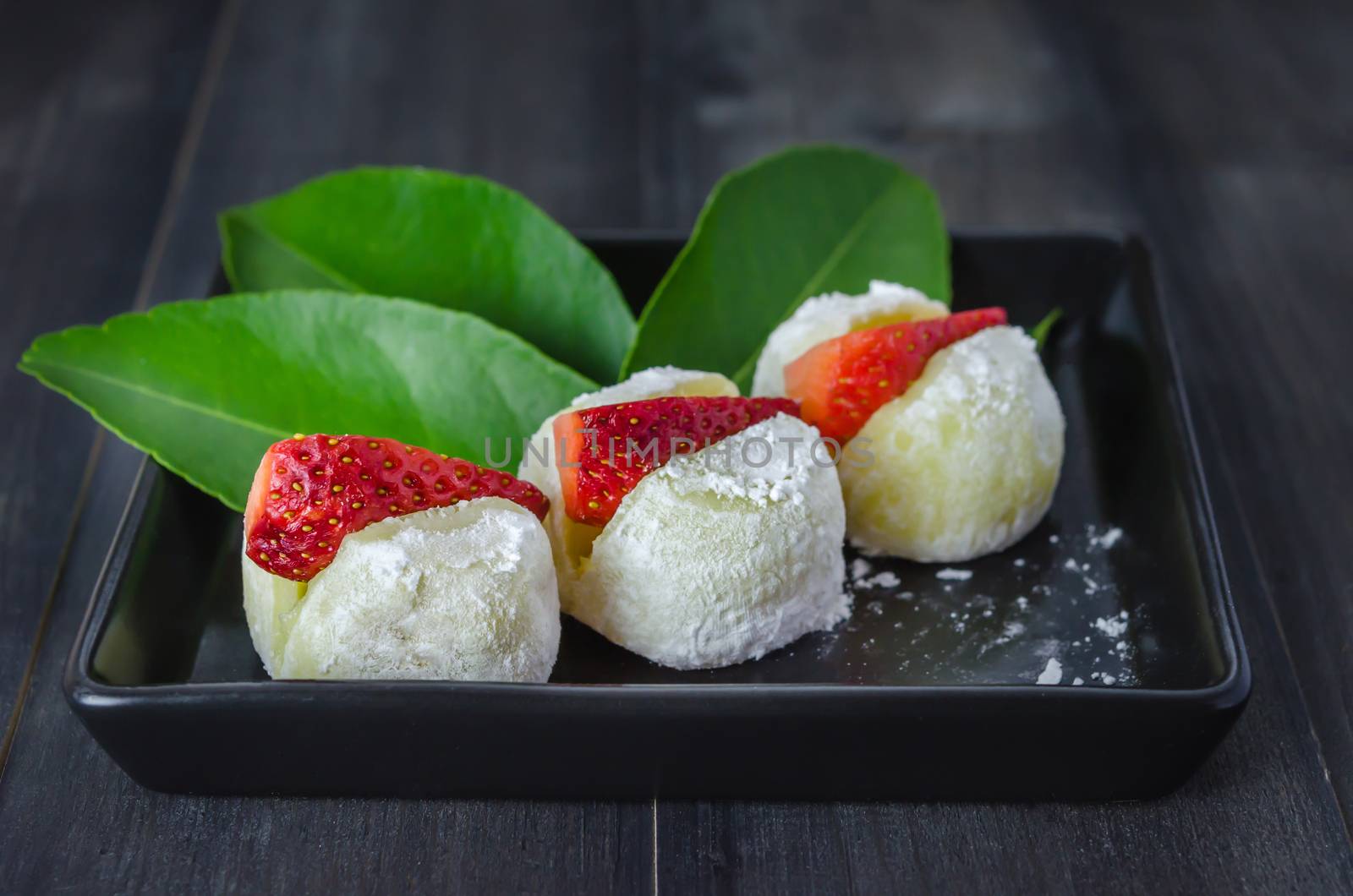 Strawberry Daifuku Mochi Japanese dessert on black dish over wooden background