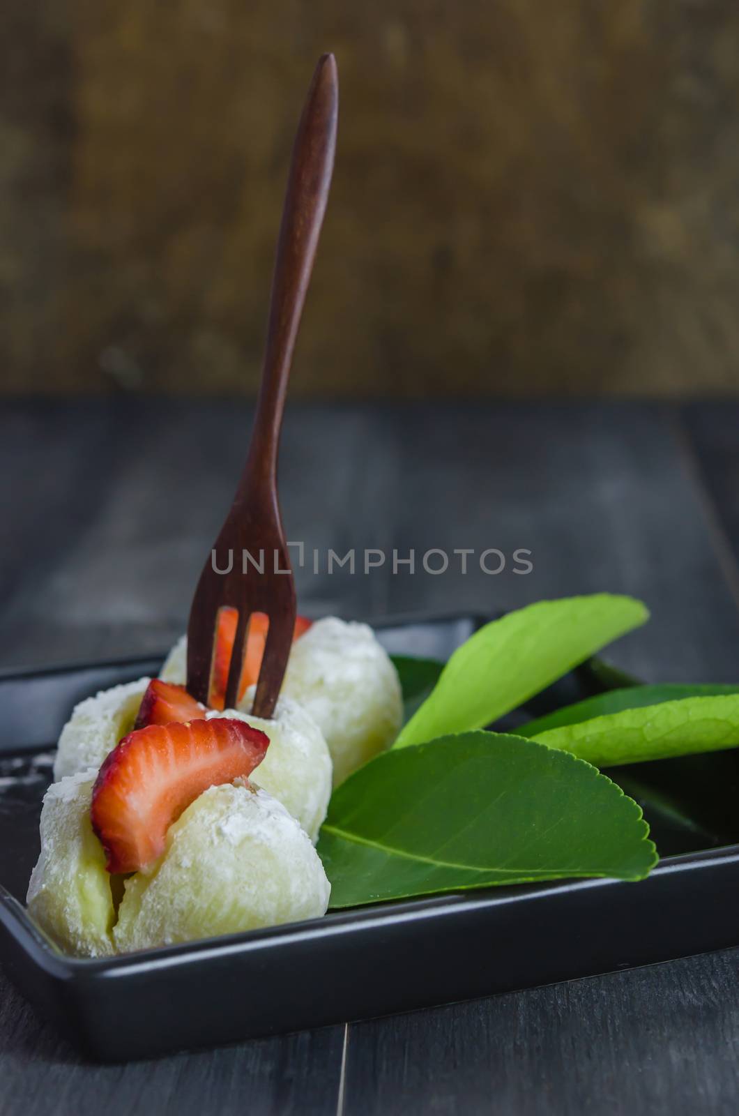 Strawberry Daifuku Mochi Japanese dessert on black dish over wooden background